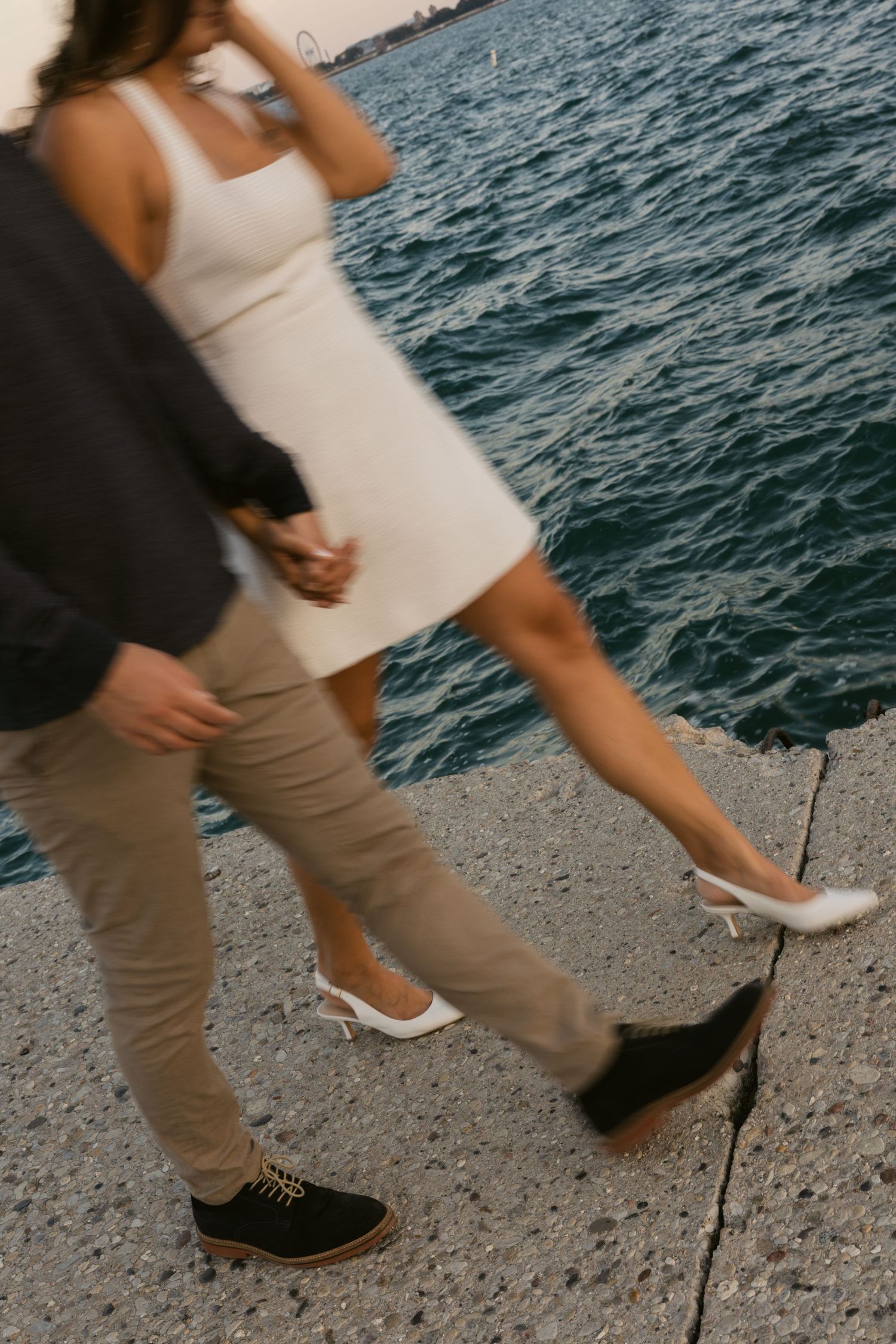 Detail shot of a couple's footwear and movement along a waterfront path.