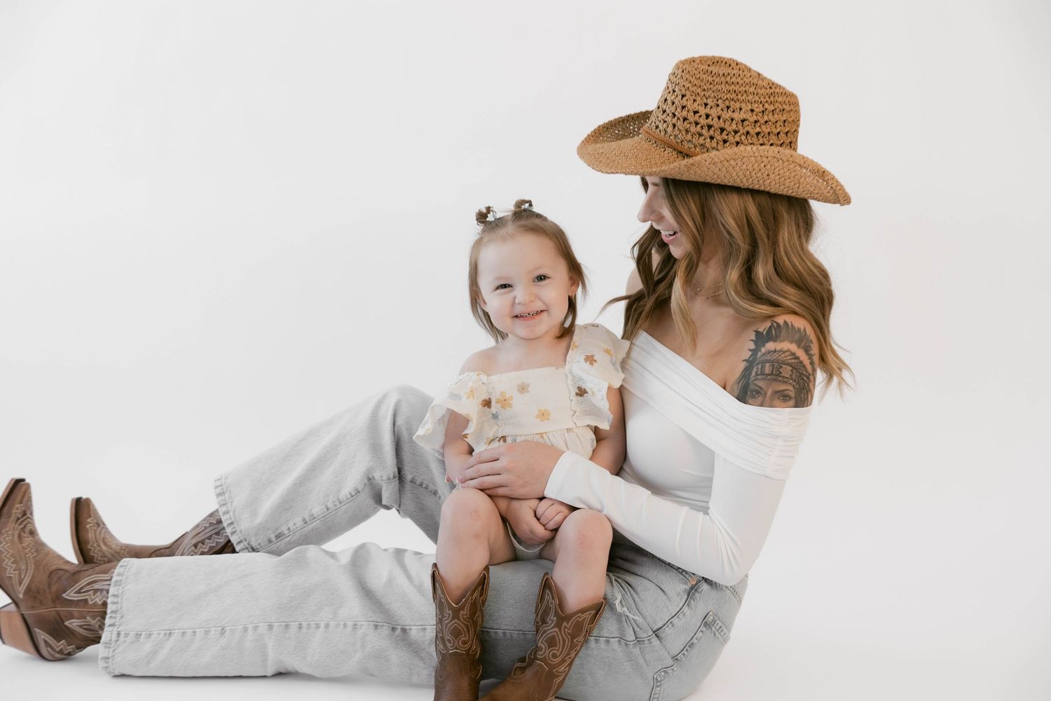 Candid moments captured during white backdrop photo session with cowboy-inspired western wear.