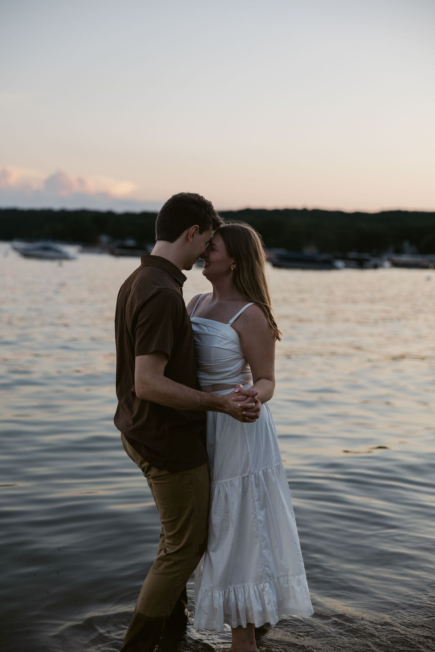 Tender moments shared between a couple on a lakeside during dusk.