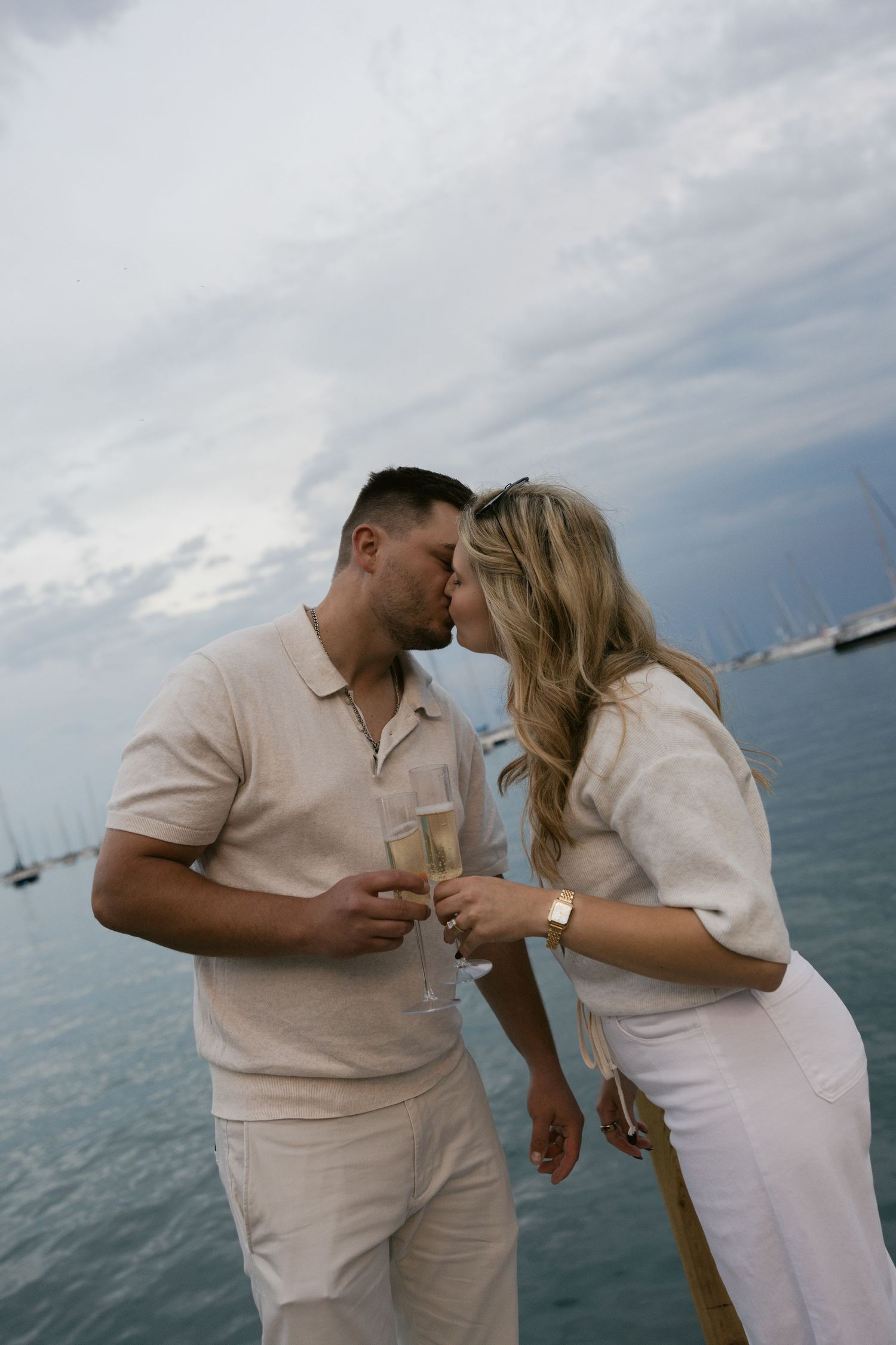 Intimate couple moment on a boat deck with cloudy ocean sky behind them.