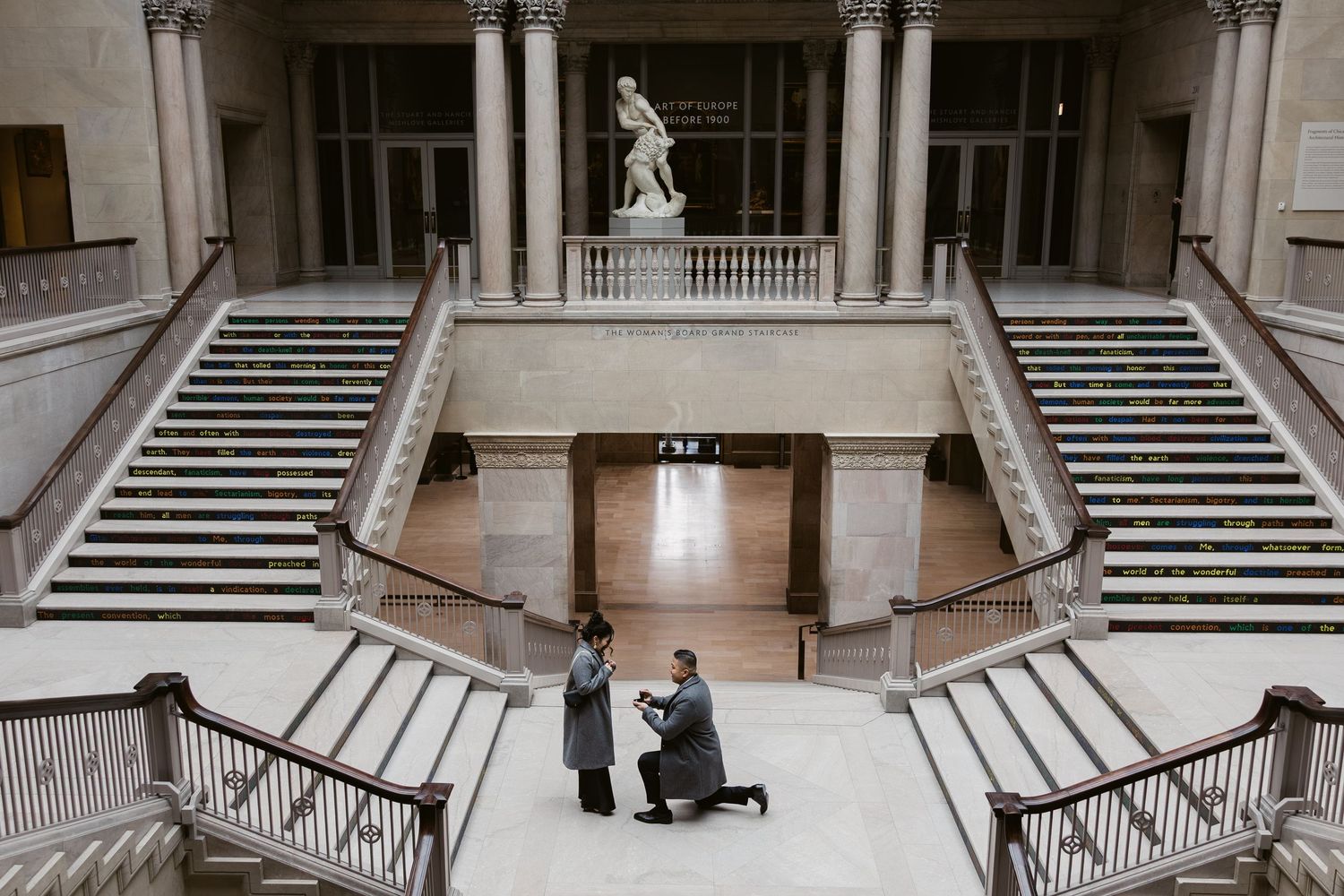 An elegant museum interior featuring marble columns and dual staircases.