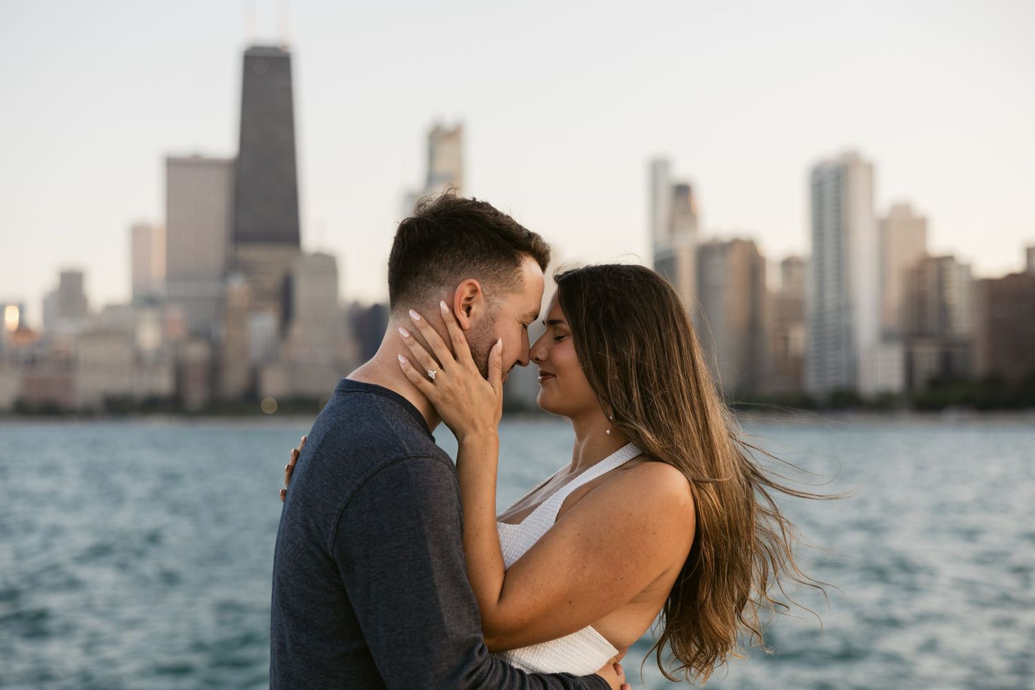 A romantic couple sharing an intimate moment with the Chicago skyline and Lake Michigan as their backdrop.