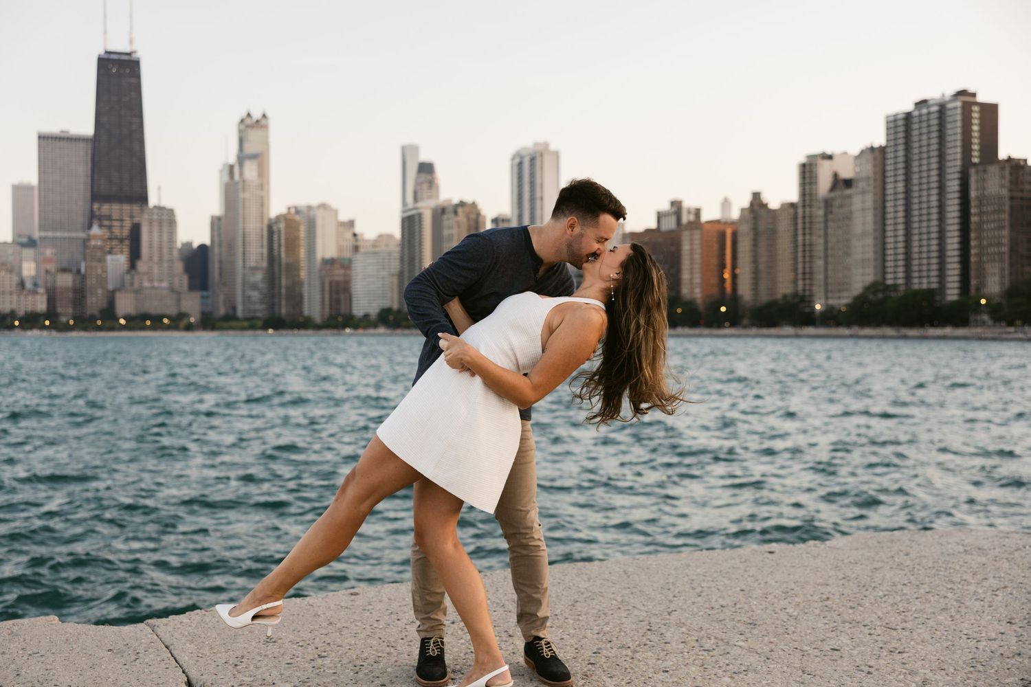 Playful couple on beach with Chicago skyline in background.