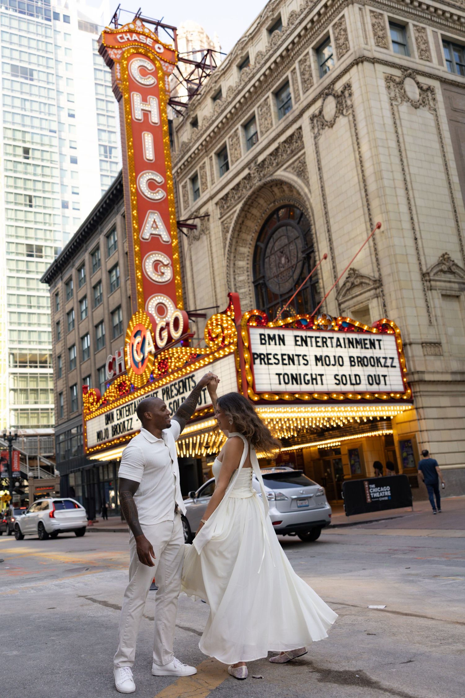 Dynamic dance sequence photographed outside historic Chicago Theater at dusk.