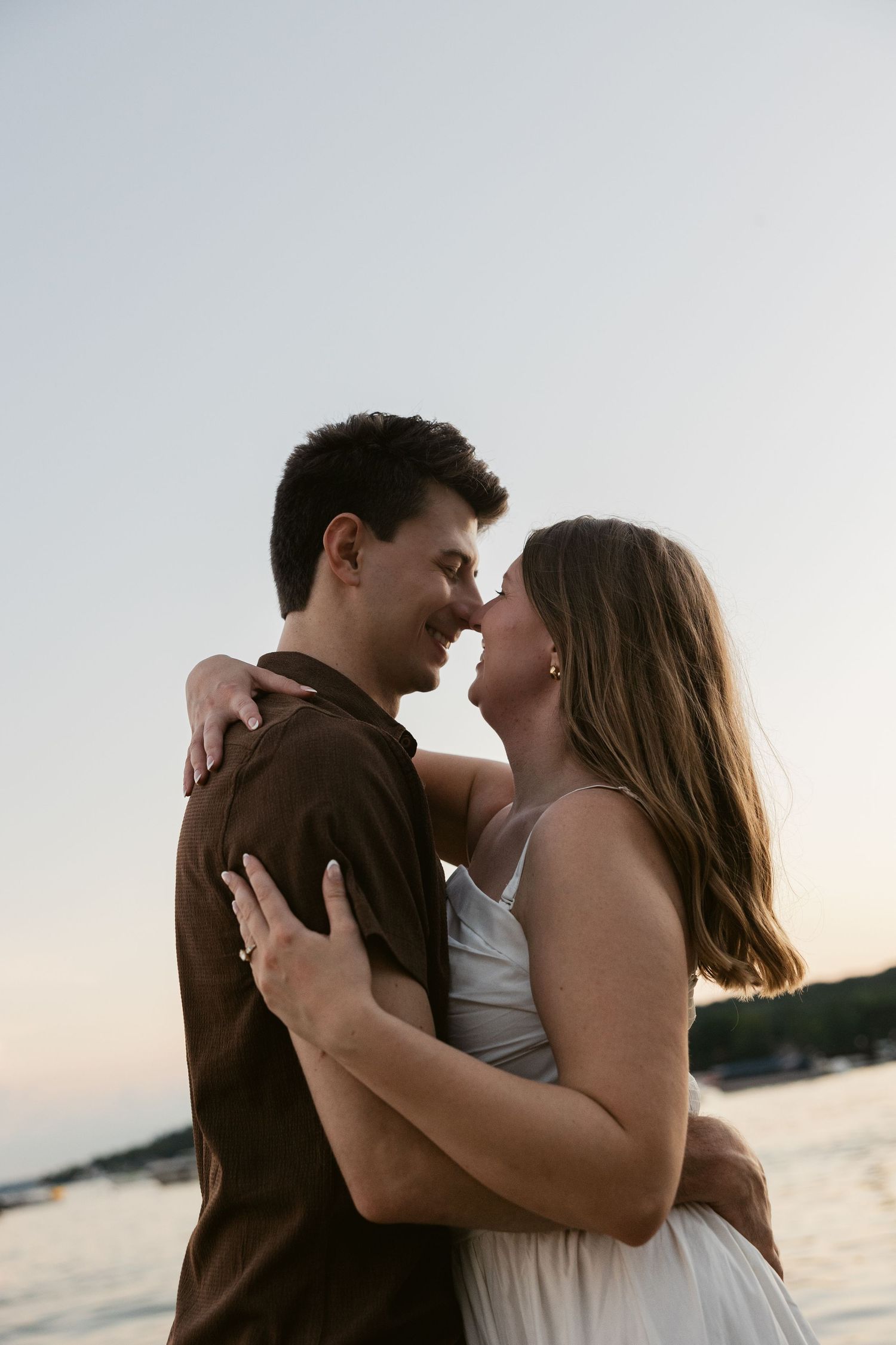 An intimate moment between a couple during their sunset photoshoot by the water.