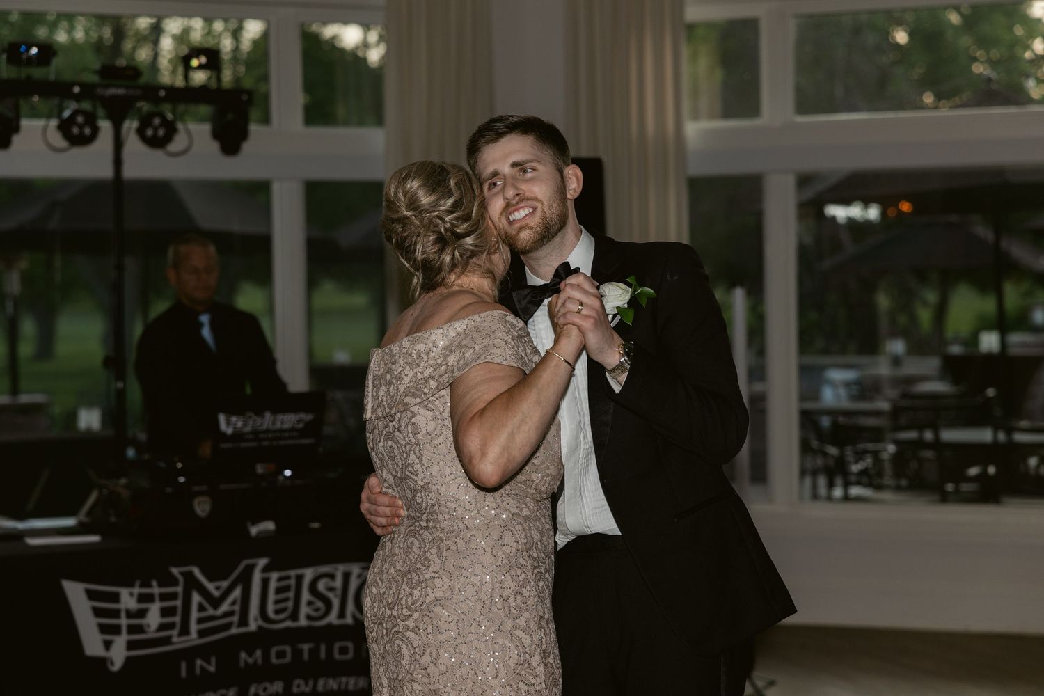 Wedding reception dance captured in an elegant venue with large windows.