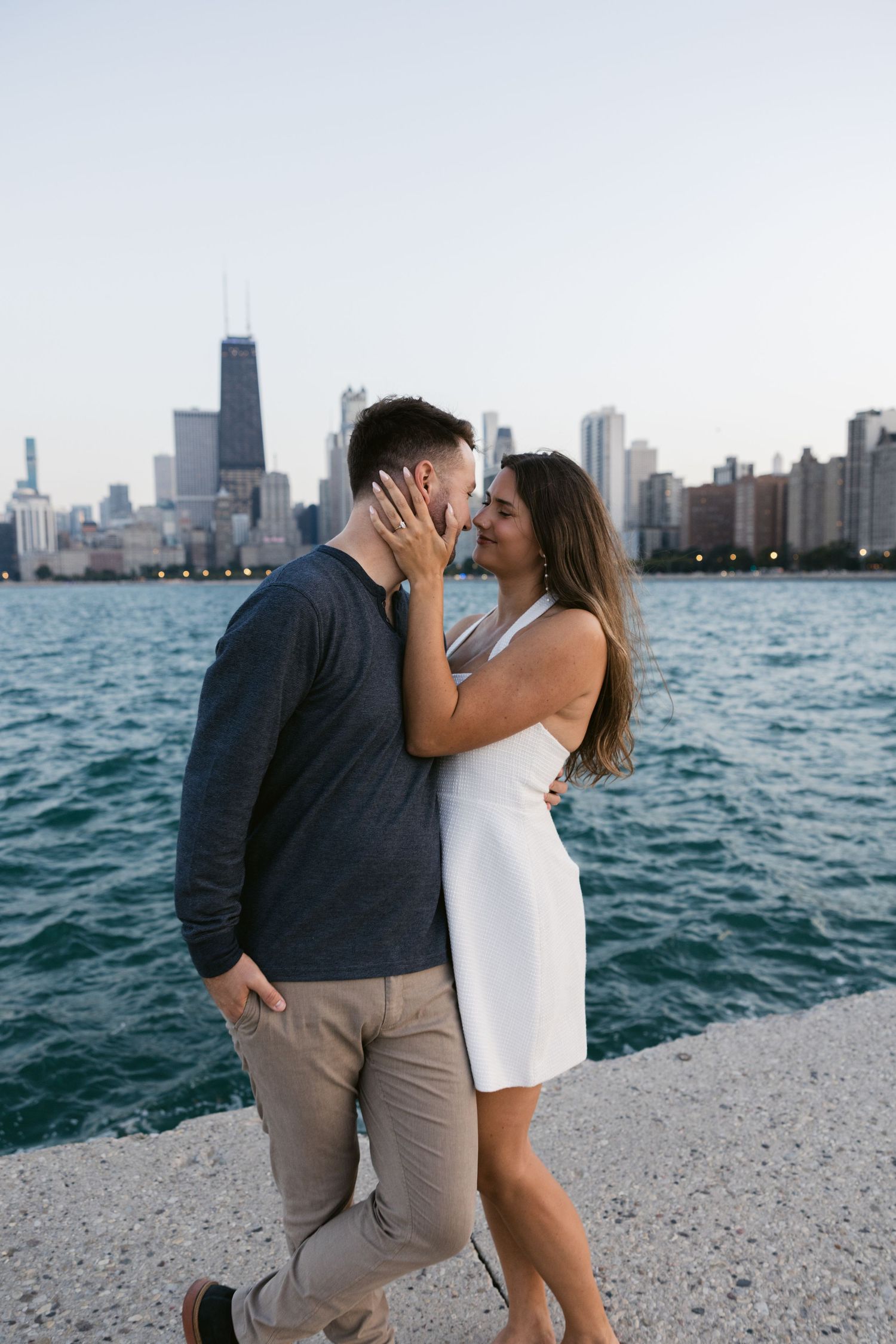 A couple shares an intimate moment on Chicago's lakefront with the city skyline visible.