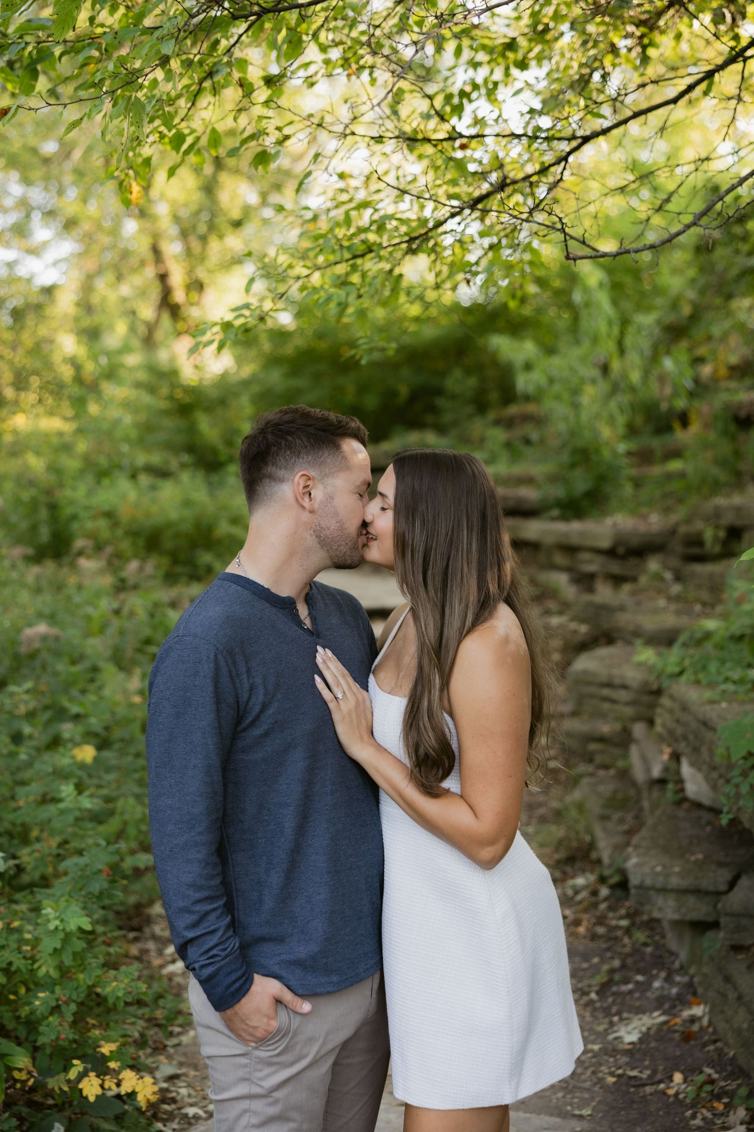 Couple shares an intimate moment against a lush green natural backdrop.