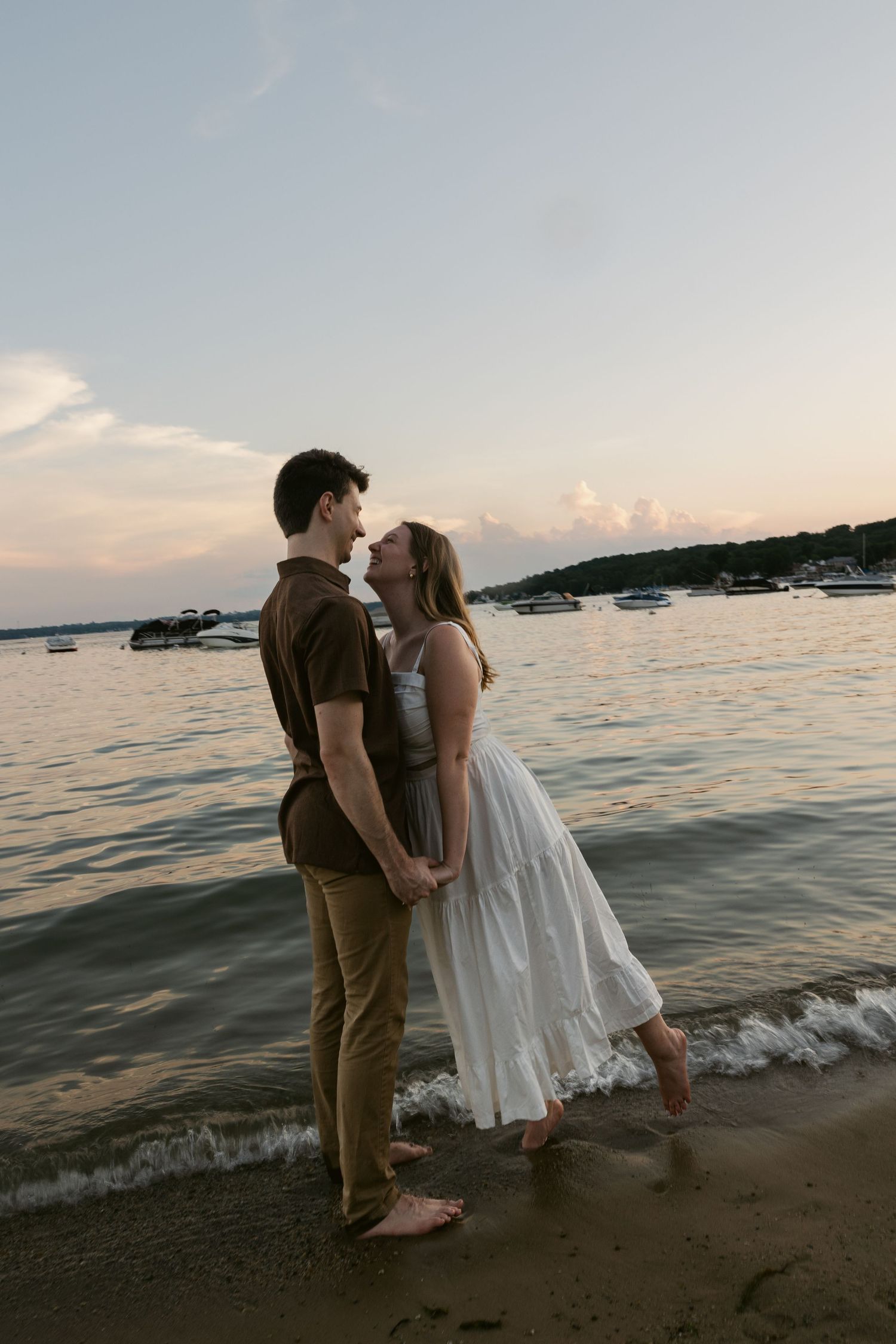 Romantic sunset photo session on a beach with boats in the background.