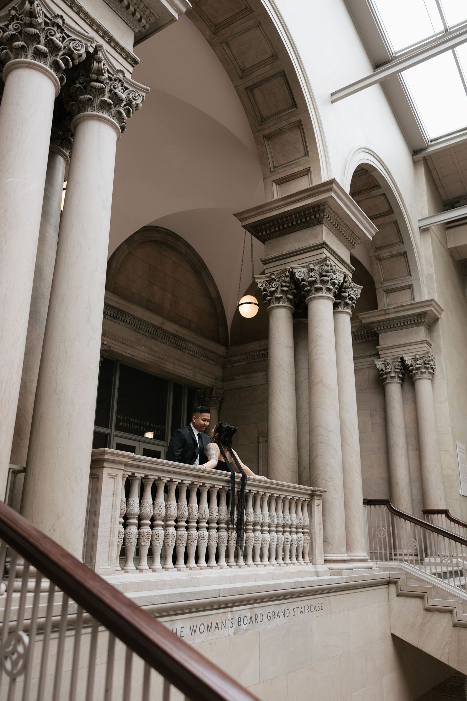 A romantic moment captured on an ornate classical balcony with Corinthian columns.