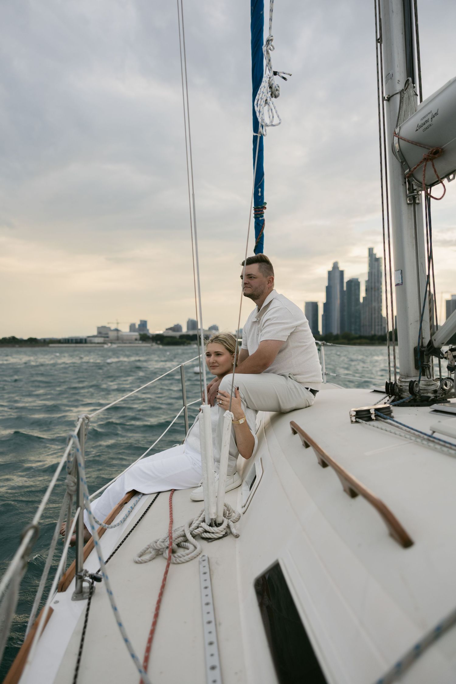 Sailing couple enjoying intimate moments on yacht deck with skyline views.