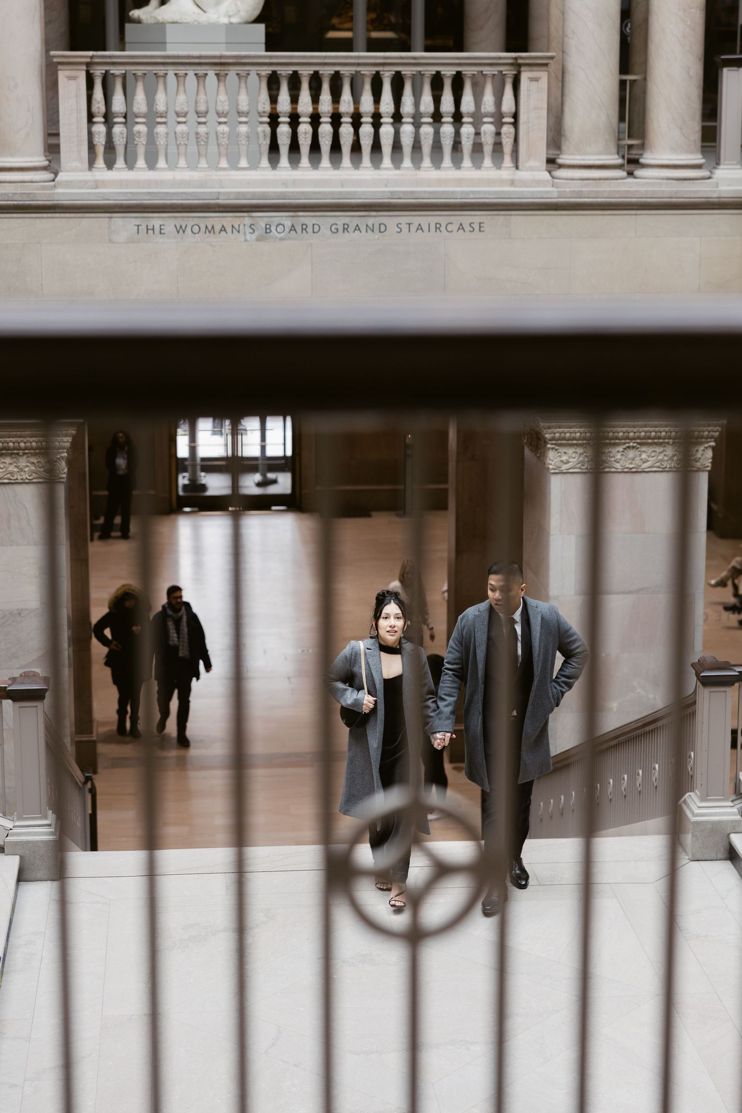 A couple photographed through architectural details in a historic building's grand staircase.