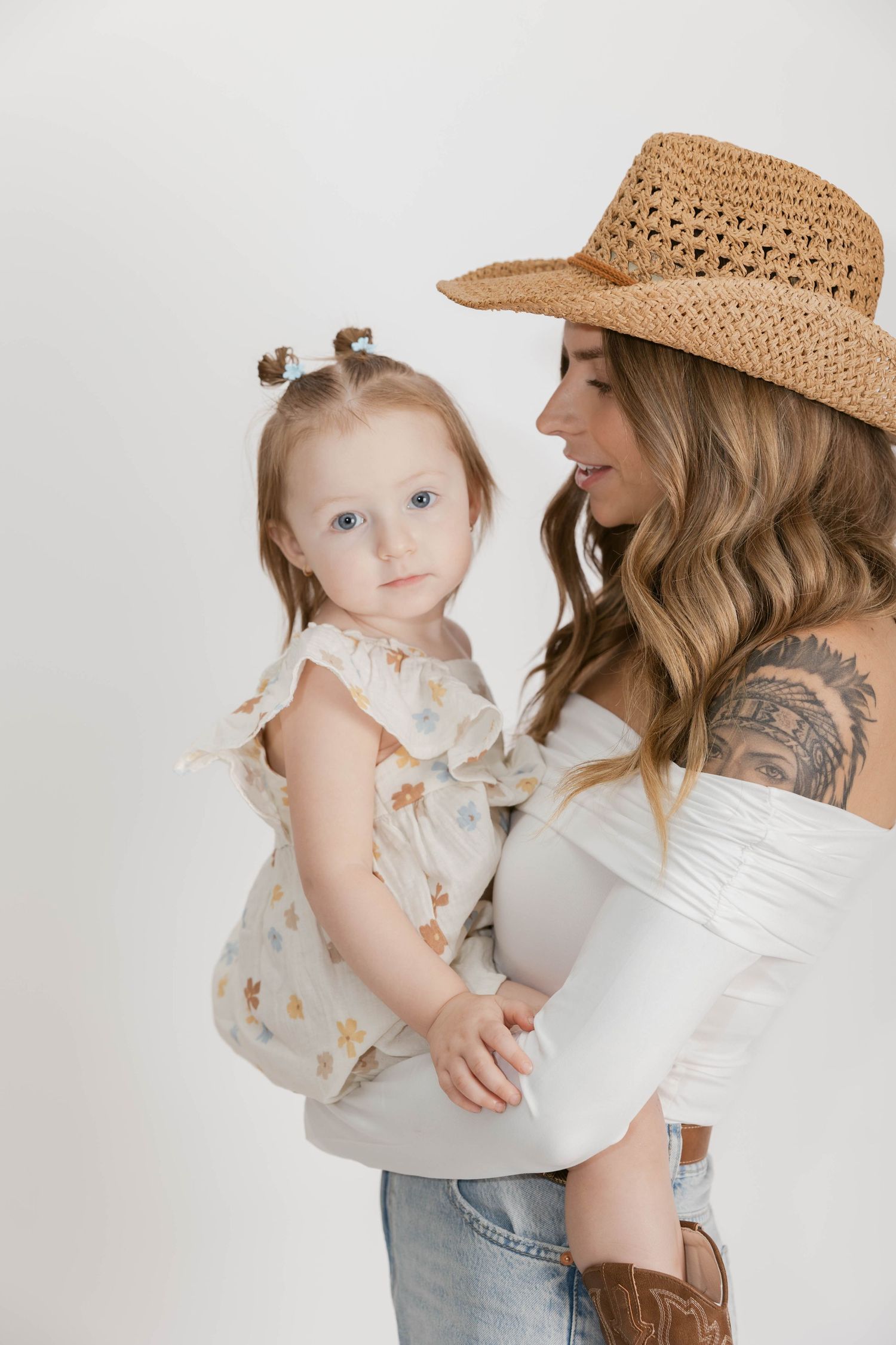 Lifestyle photo of parent and child in straw hat against white background.