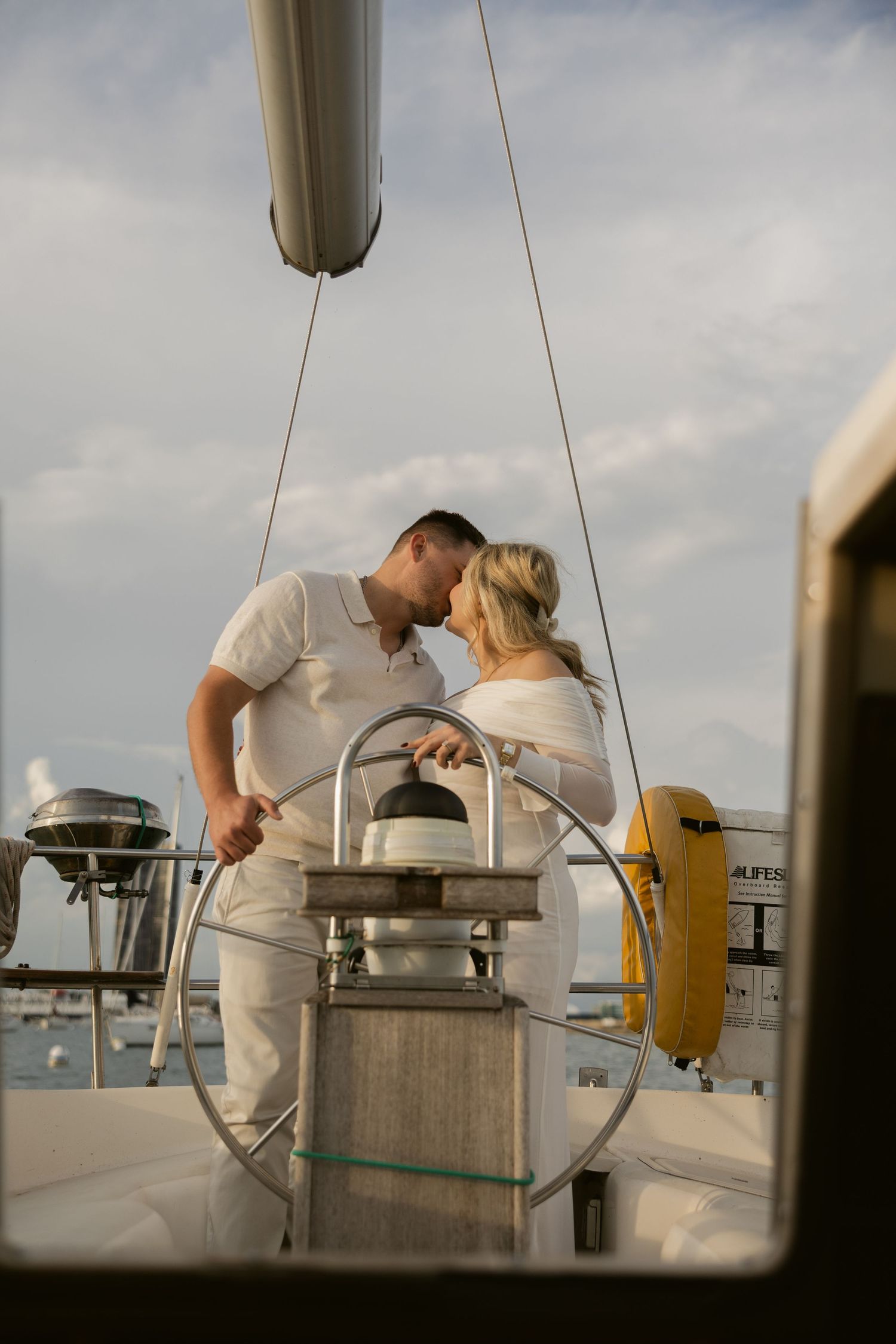 A romantic moment captured on a sailboat's deck with the city skyline visible in the distance.