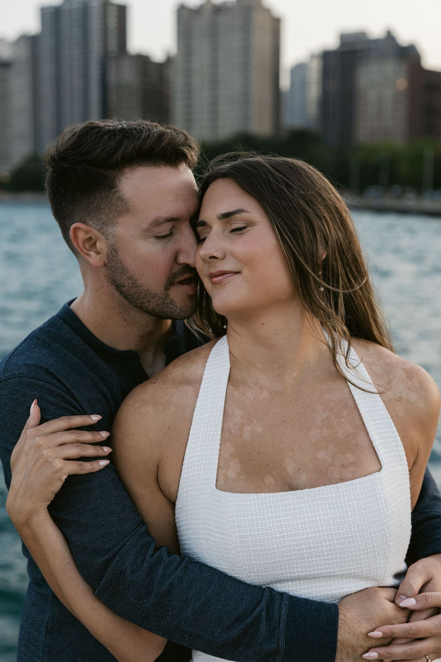 An intimate couple shares tender moments by Lake Michigan with Chicago's skyline in the background.