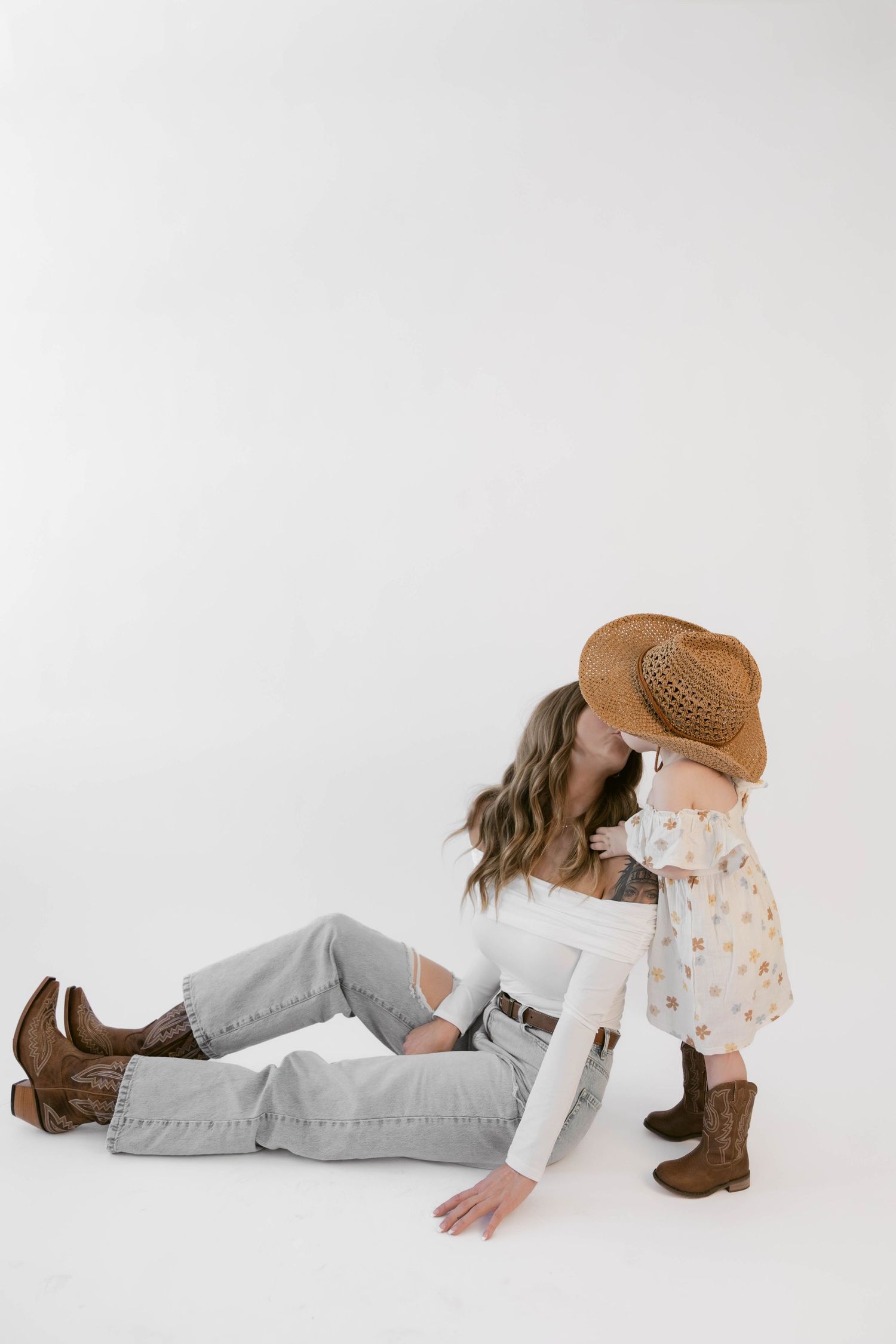 White studio photos showcase intimate family moments in western-inspired outfits.