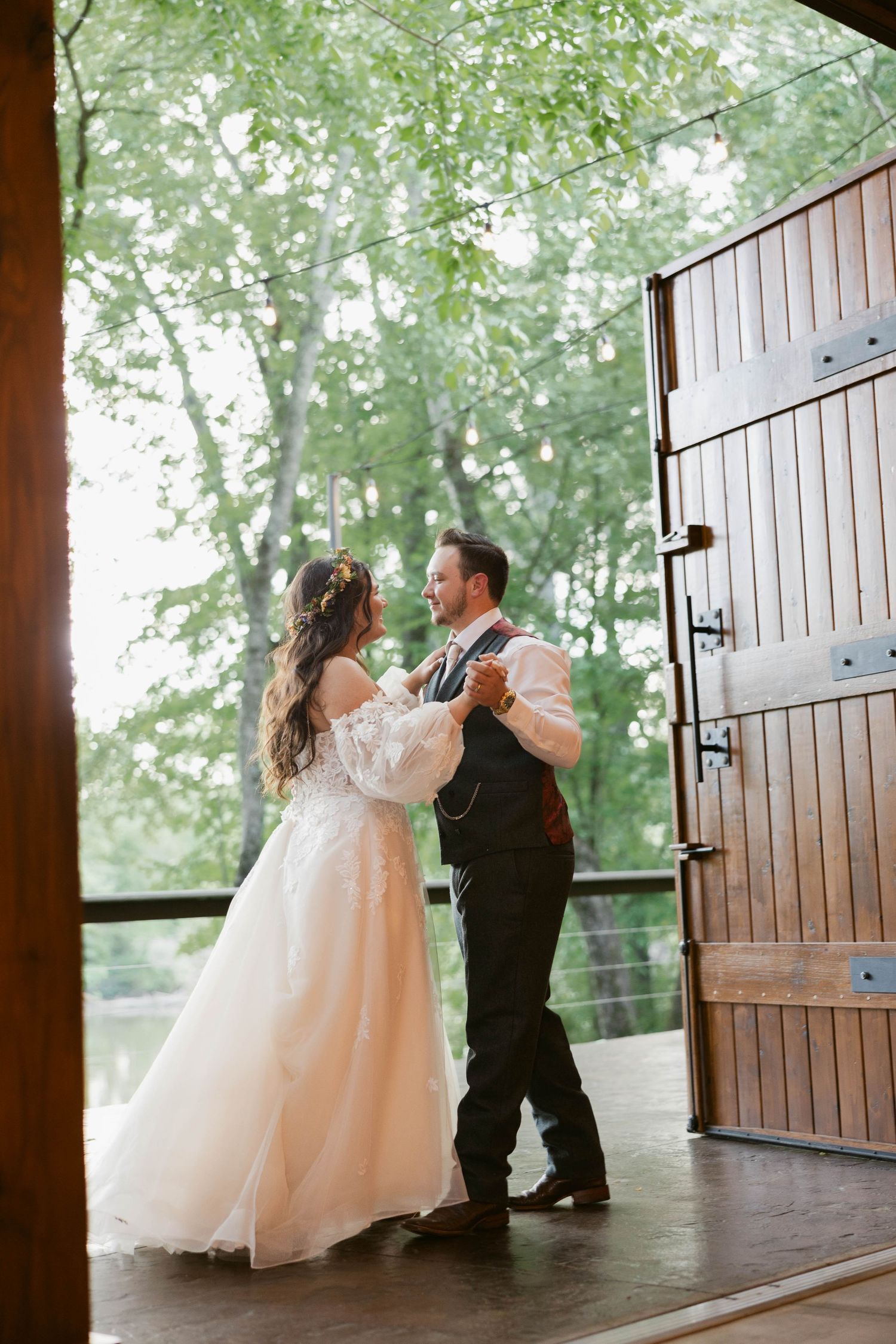 Couple dancing on covered porch with rustic wooden door and natural backdrop.