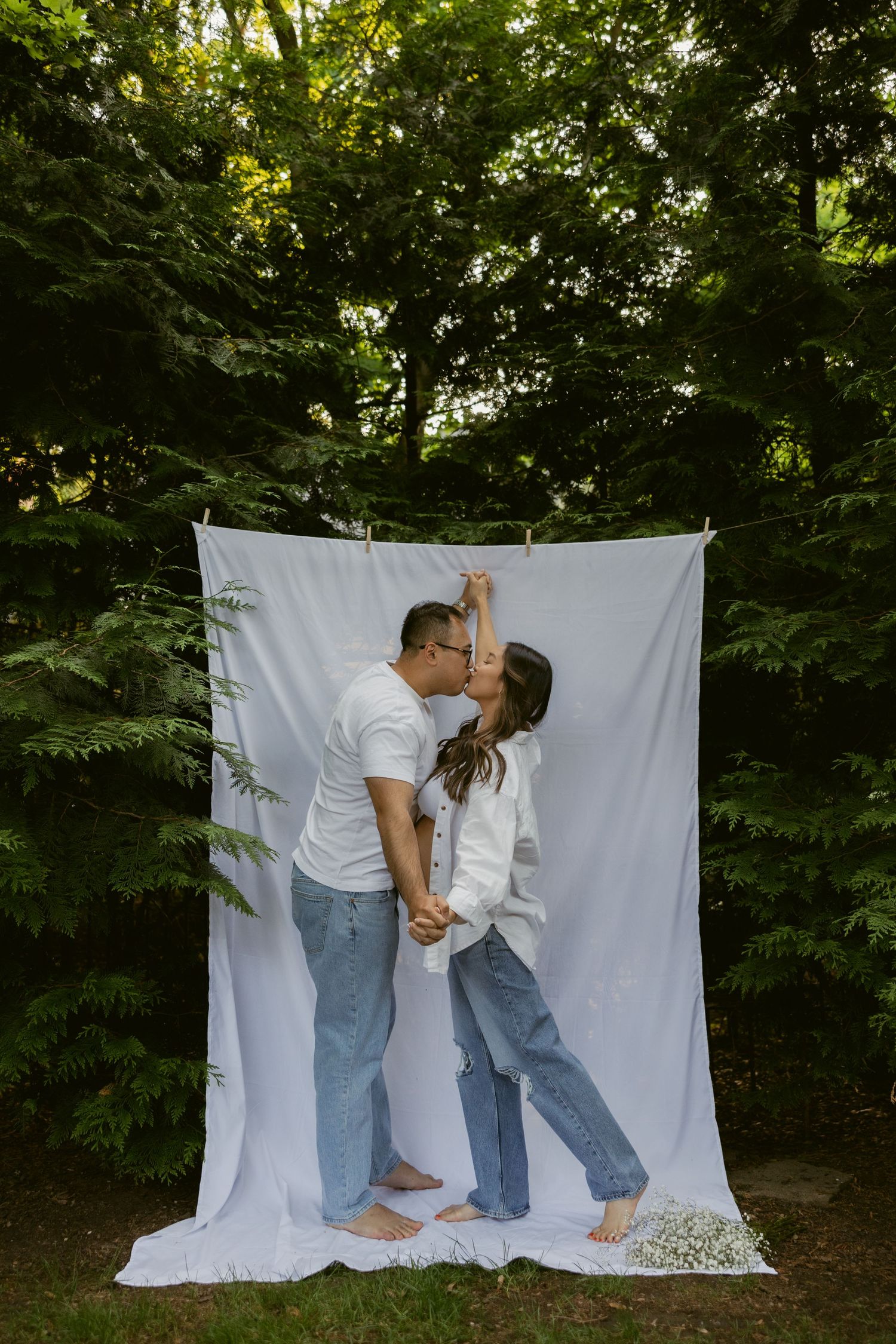A romantic outdoor photoshoot with a couple sharing an intimate moment against a white backdrop.