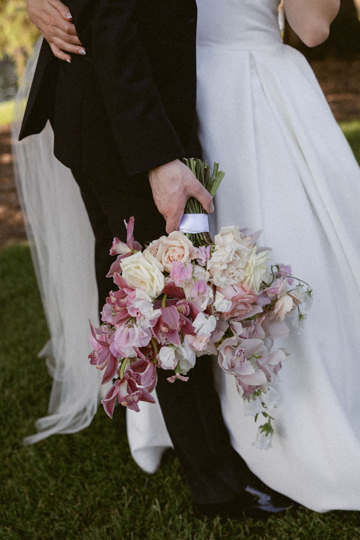 Close-up of delicate pink and cream wedding bouquet against formal wedding attire.