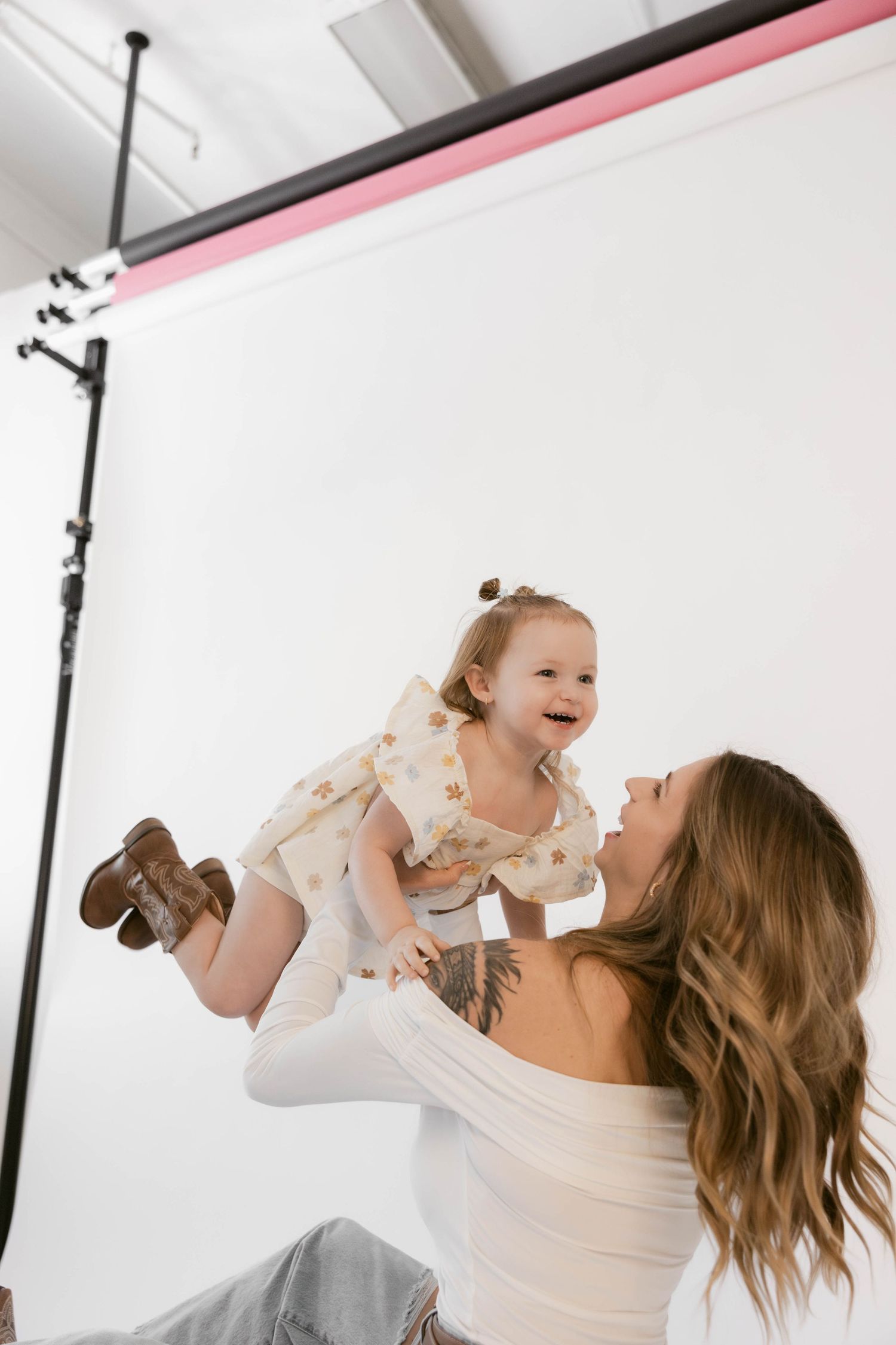 A joyful moment between parent and toddler during a photo shoot against a white backdrop.