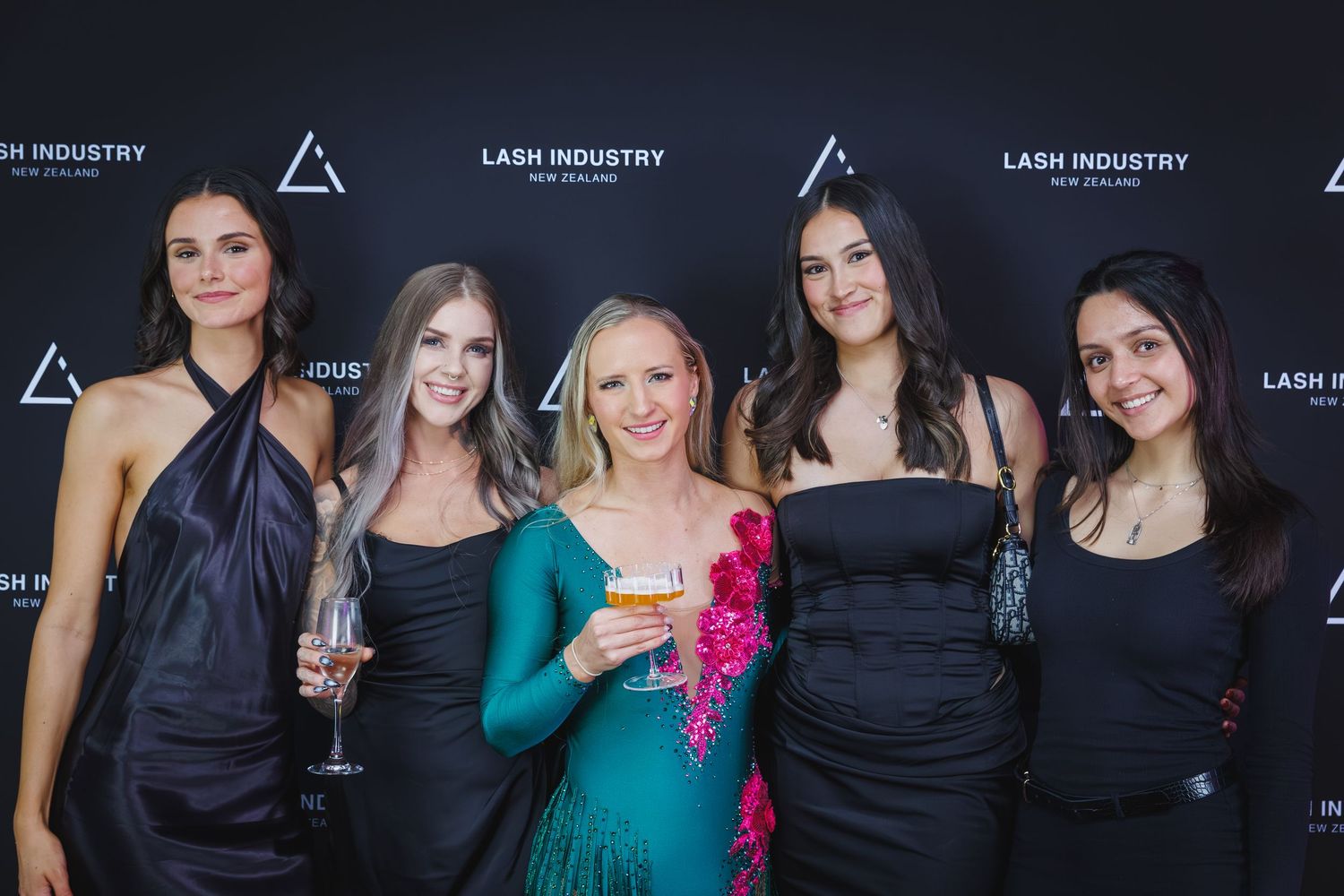 Five elegant women posing at Lash Industry New Zealand awards event branded step-and-repeat.