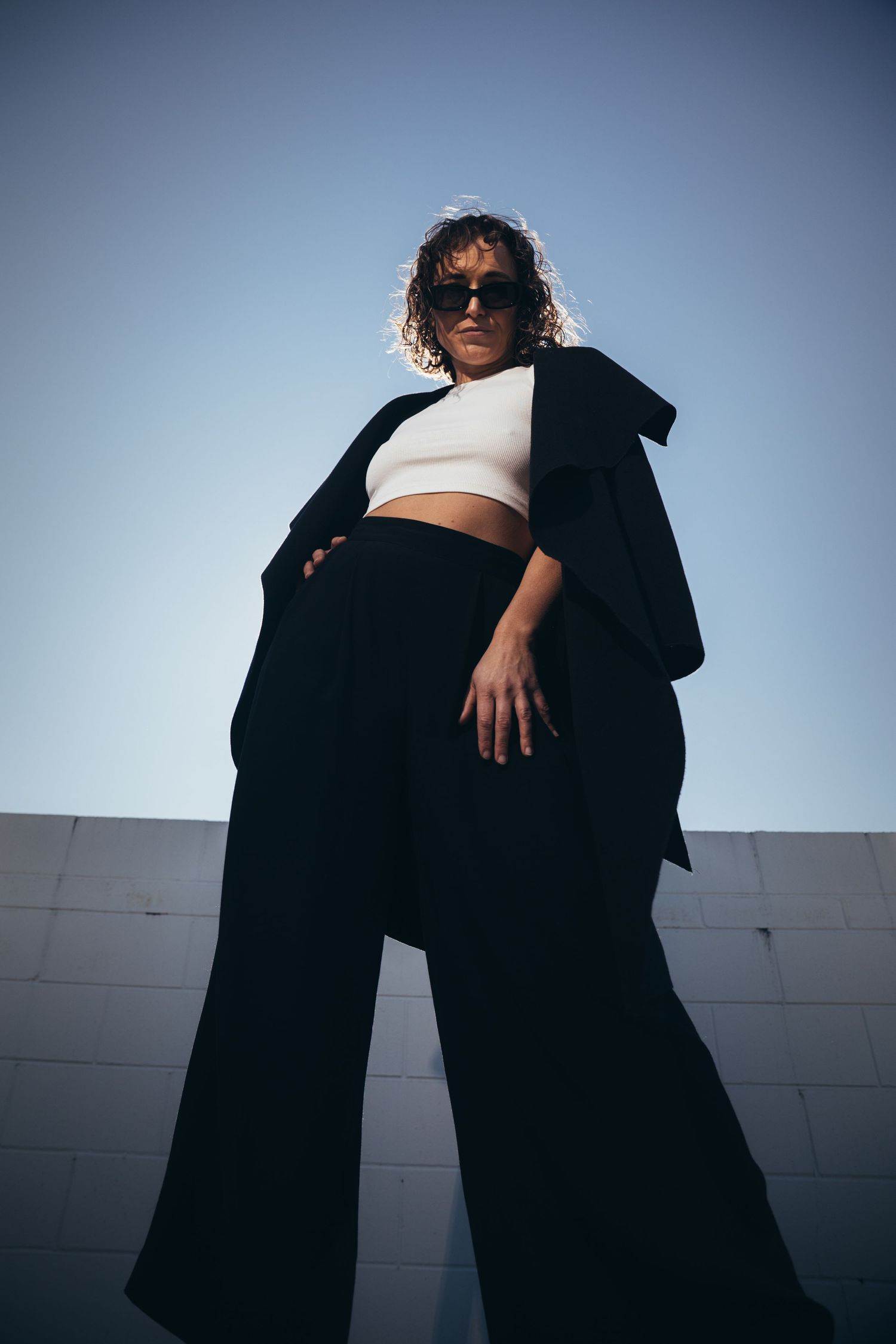 Confident woman standing tall above the camera wearing black and white clothing