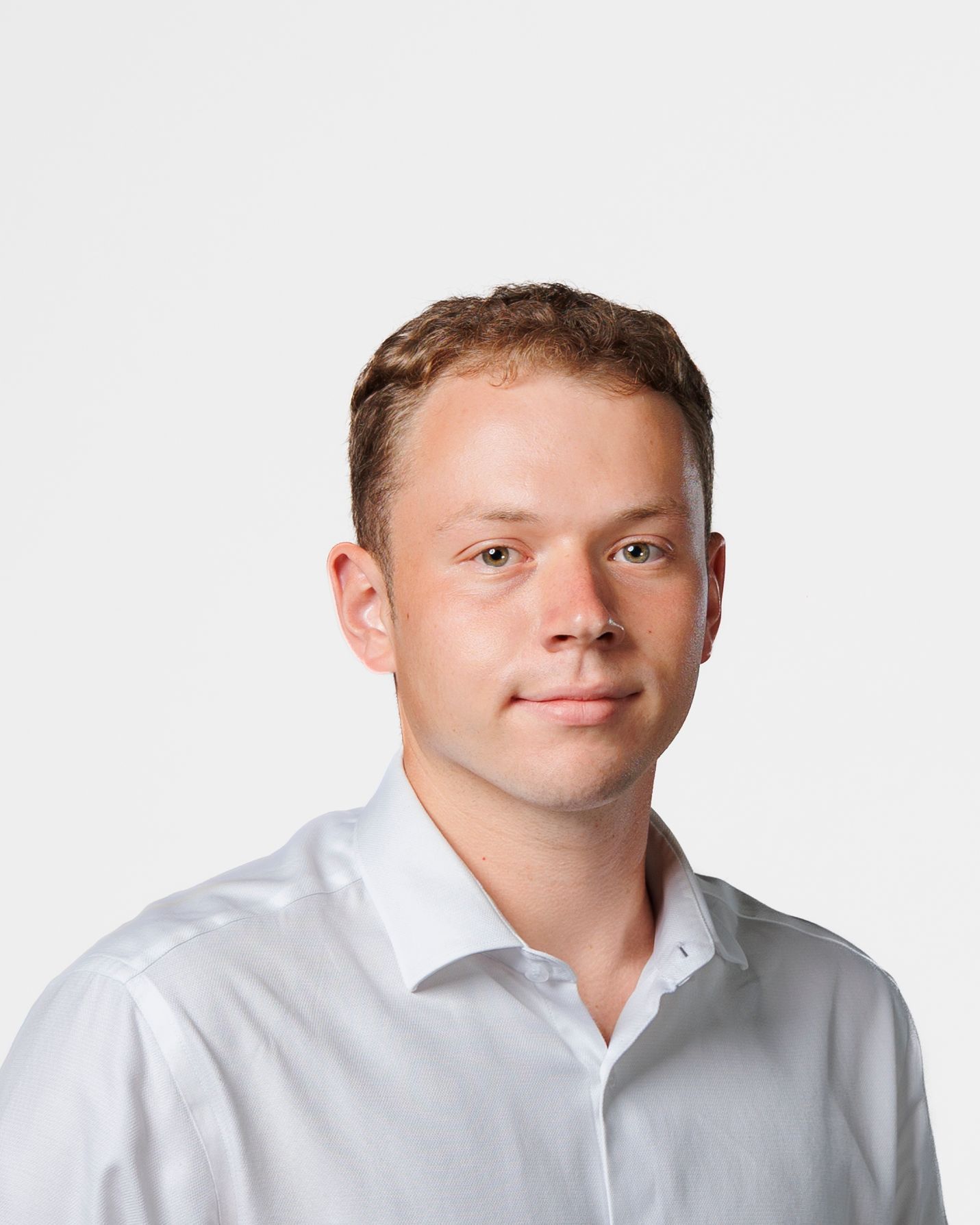 Professional headshot of a young man with short brown hair wearing a white button-up shirt against a white background.