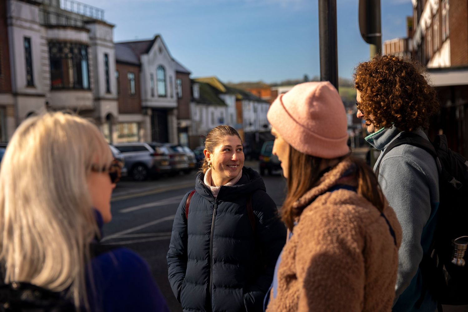 Group of four friends chatting at a sunny street corner in a small town.