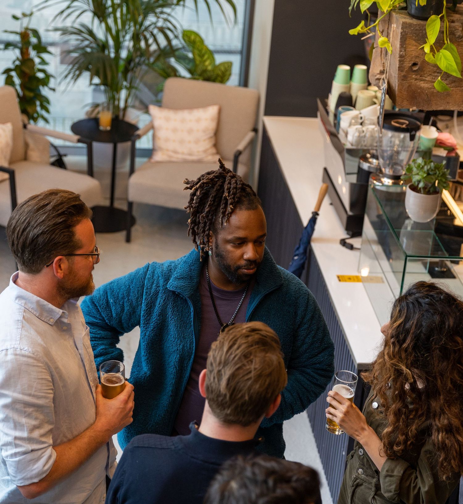 Diverse group of professionals socializing with drinks at a modern co-working space event.