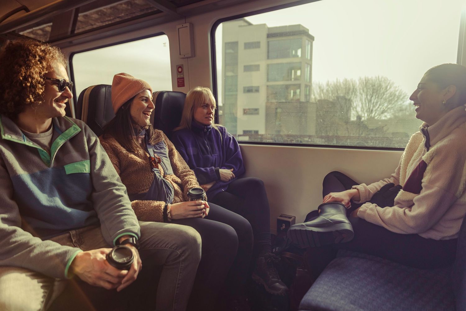 Group of four friends sitting and chatting on a train during a journey through the city.