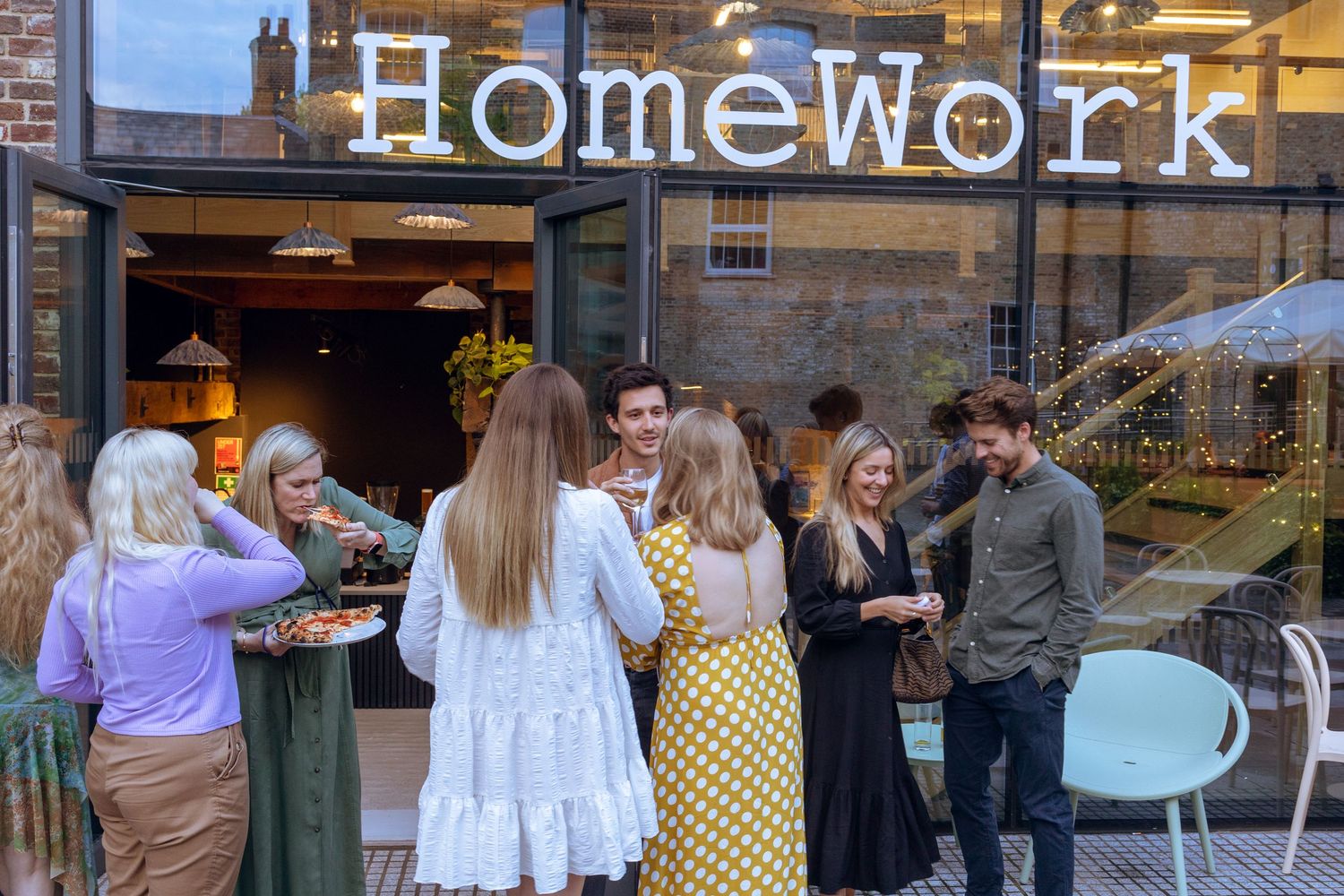 Group of guests socializing outside HomeWork venue entrance during an evening event.