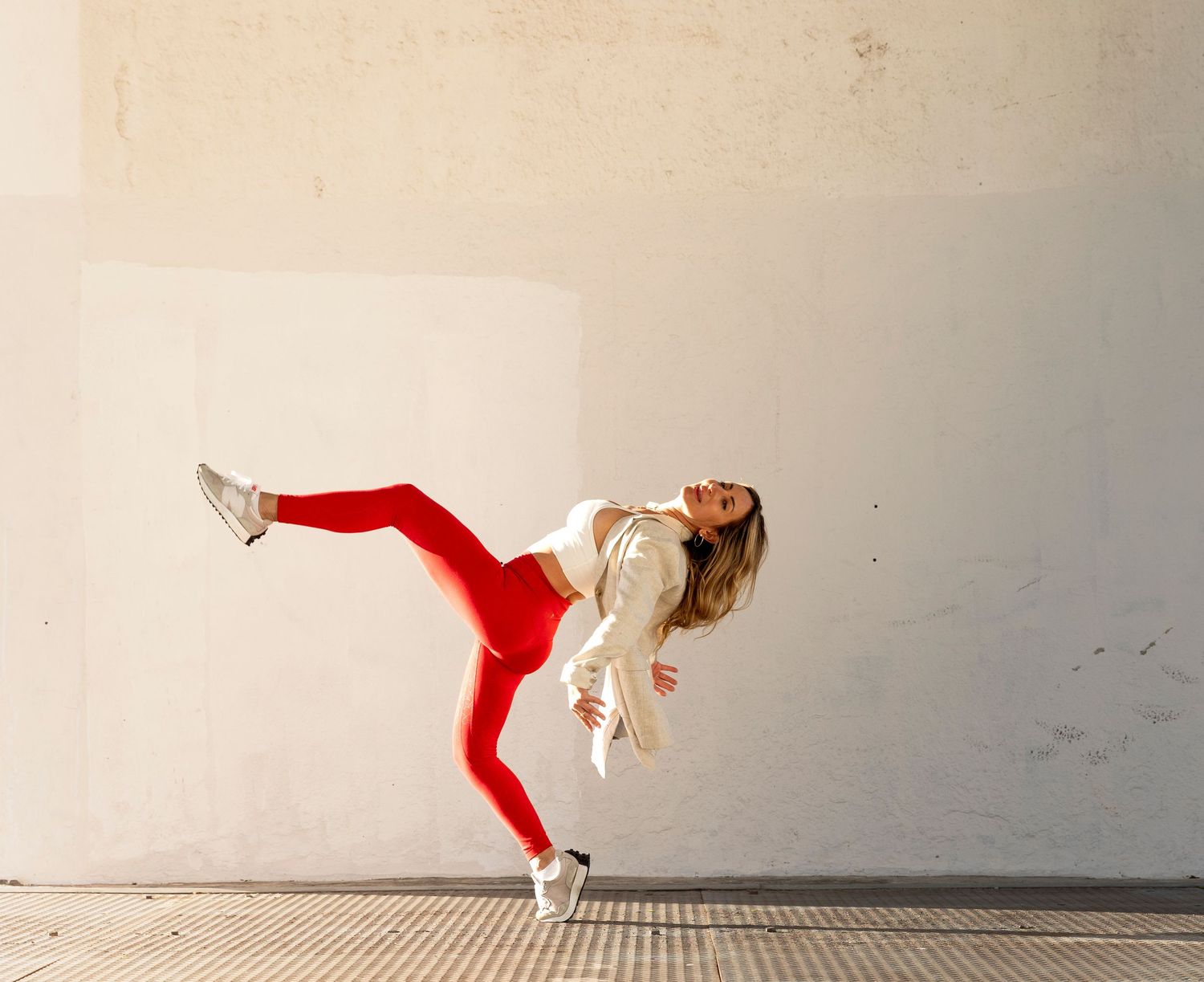 Female dancer in red leggings and white jacket performing a dynamic lean balance move.