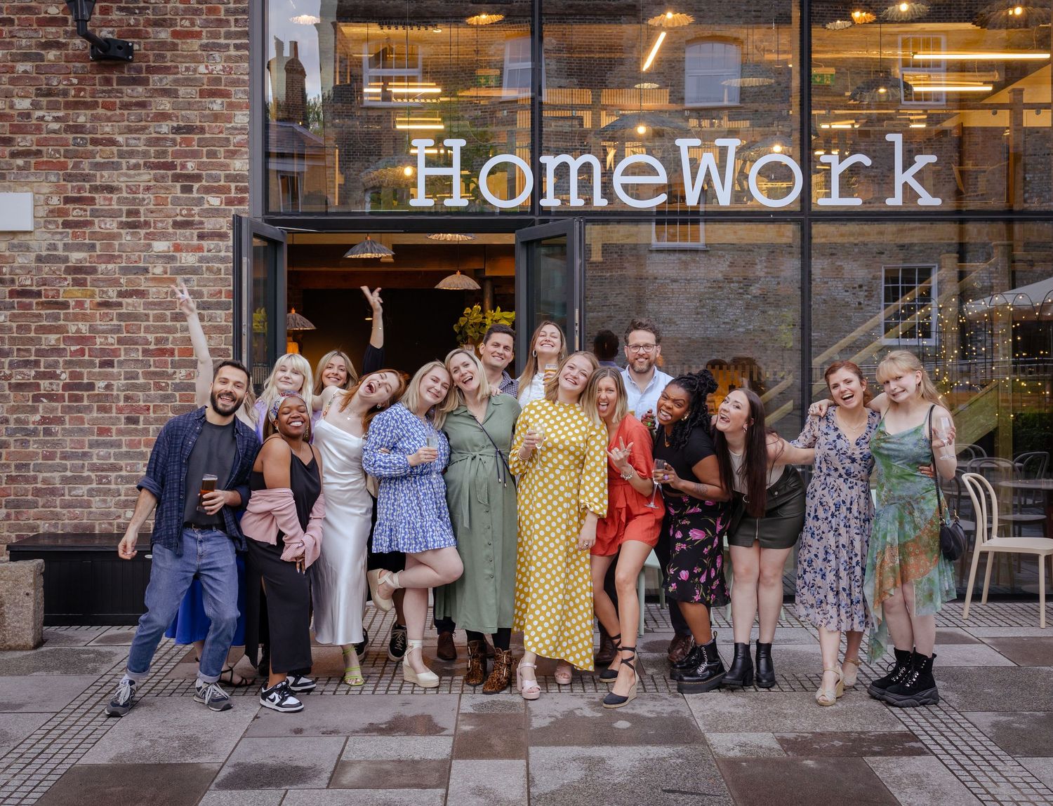 Large group of smiling guests pose together outside the HomeWork venue for a group photo.