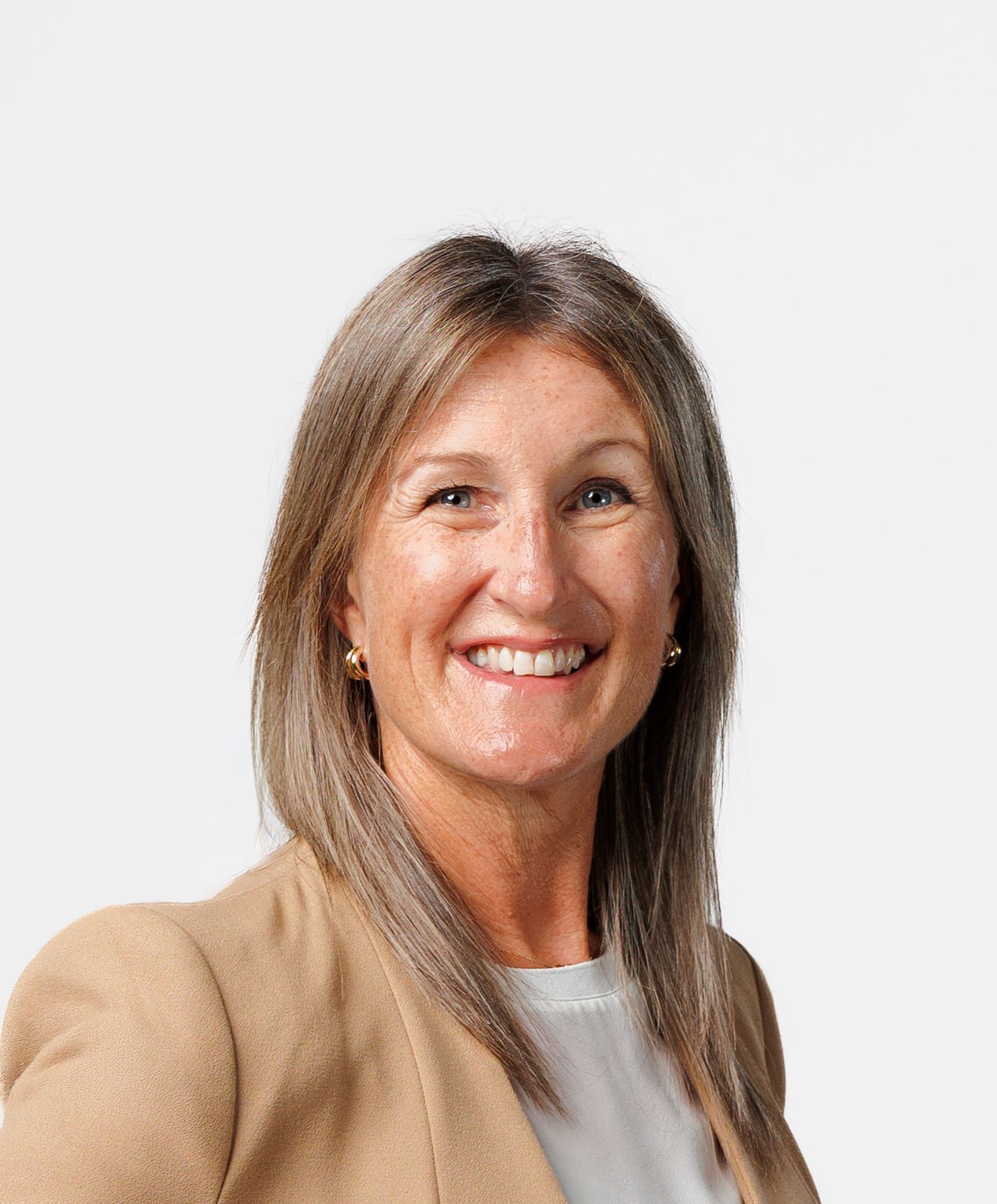 Professional headshot of a smiling middle-aged woman with brown hair wearing a beige blazer against a light background.