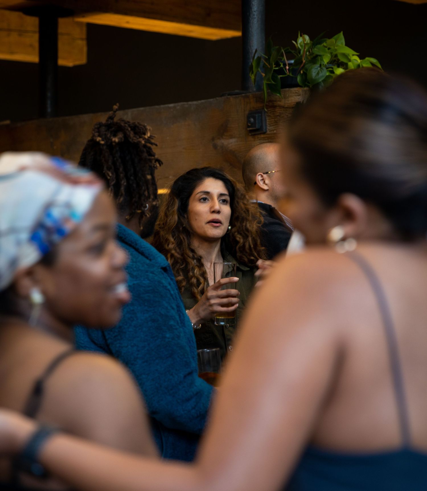 Women engaged in conversation at a dimly lit indoor social networking event.