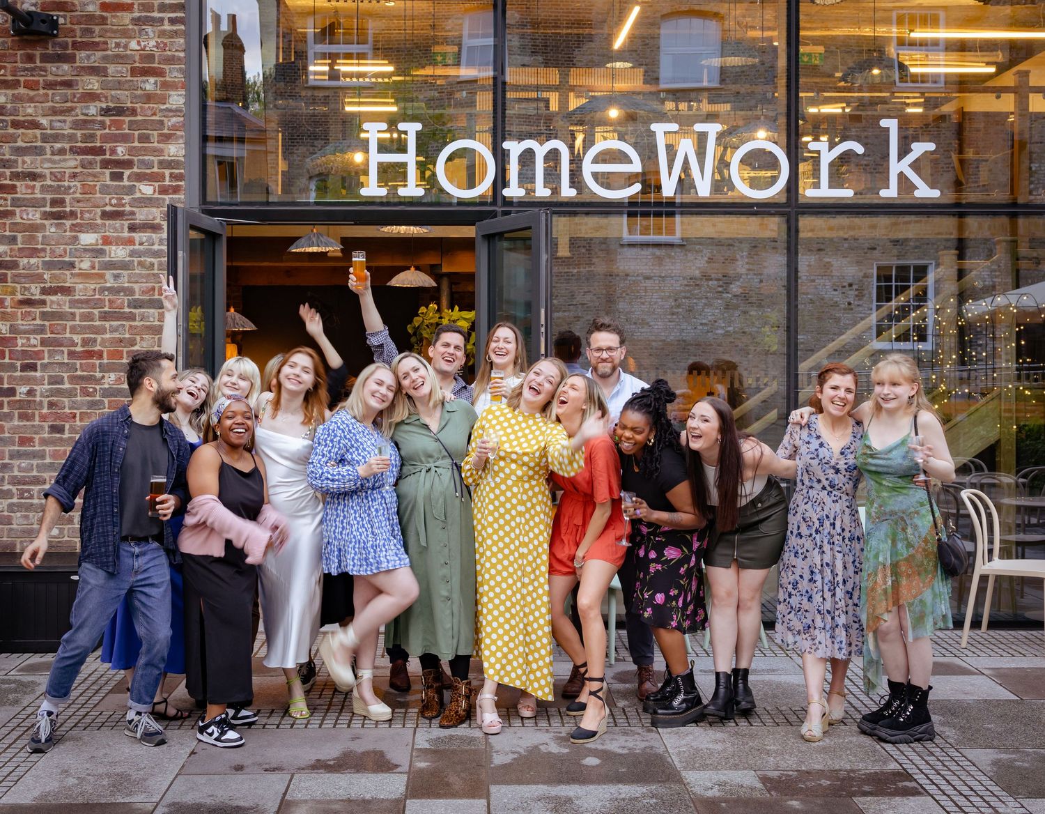 Energetic group of friends celebrate outside HomeWork venue, laughing and posing together.