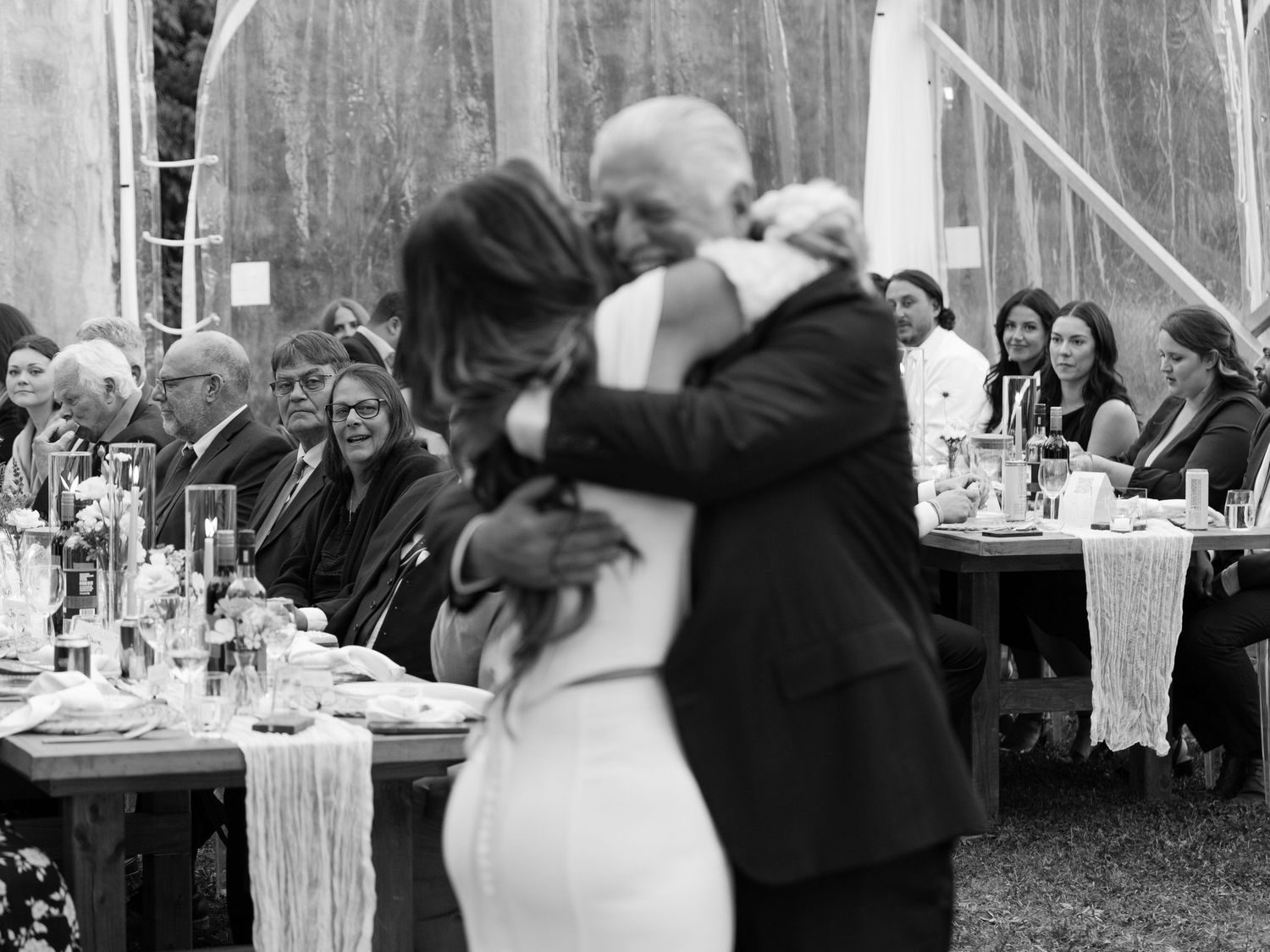 Bride and older man share emotional embrace on dance floor during father-daughter dance at wedding reception.
