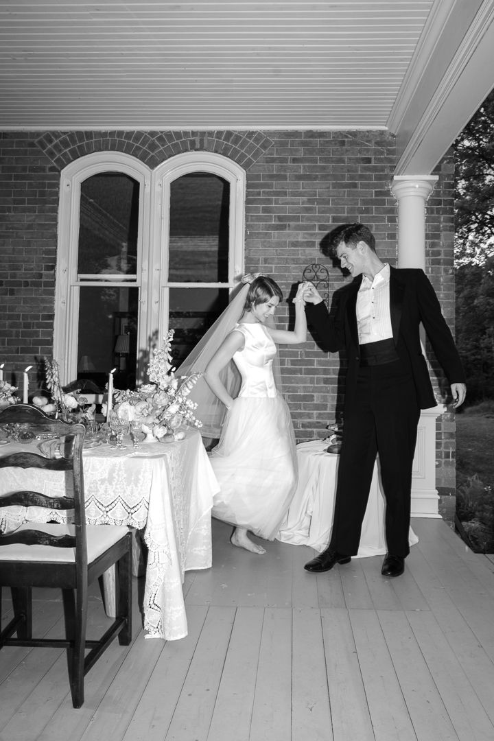 Bride and groom share a first dance on a brick building porch in black and white wedding photo.