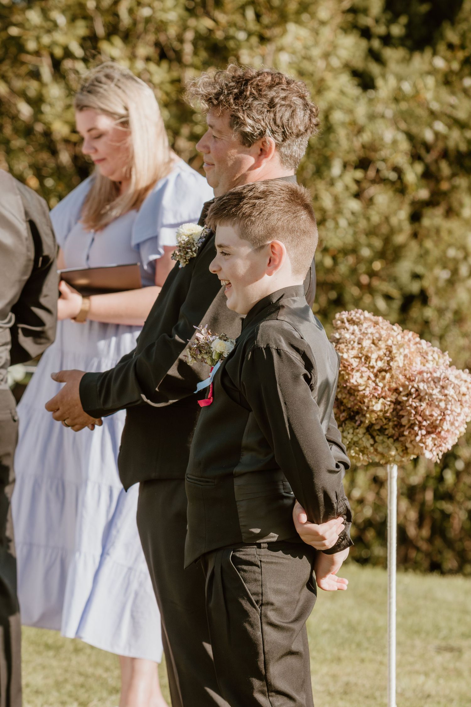 Three candid photos of emotional reactions during an outdoor wedding ceremony, with dark suits and white attire visible.