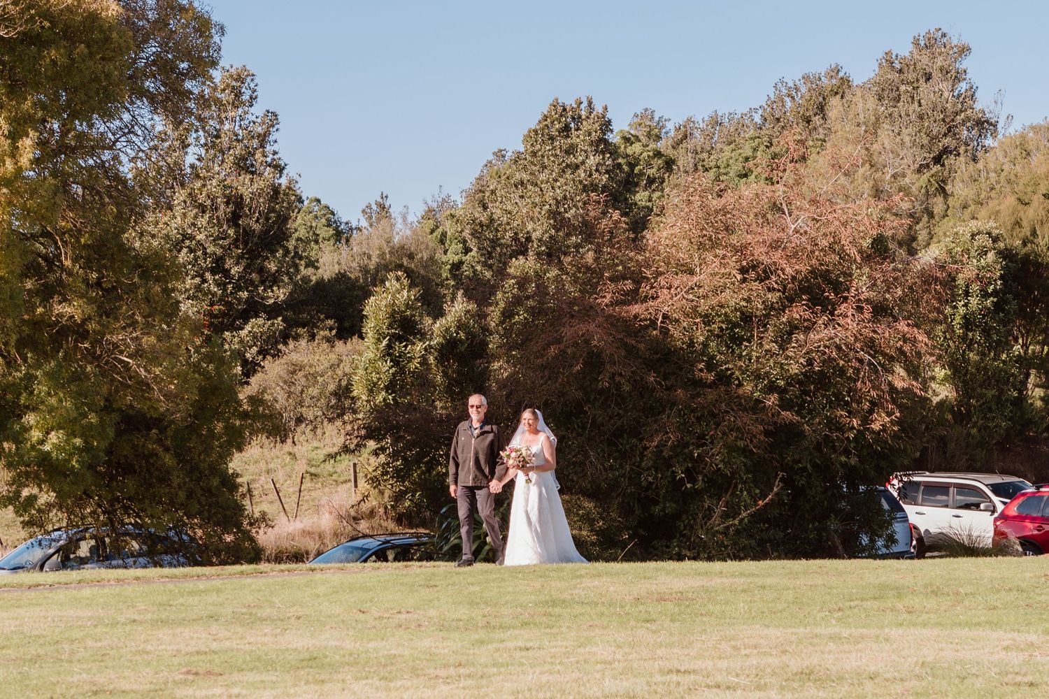 Wedding couple walks together under colorful autumn trees during their fall outdoor photo session.