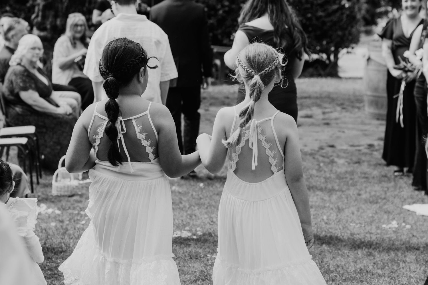 Wedding guests dance and celebrate on an outdoor lawn during a festive reception party in black and white.