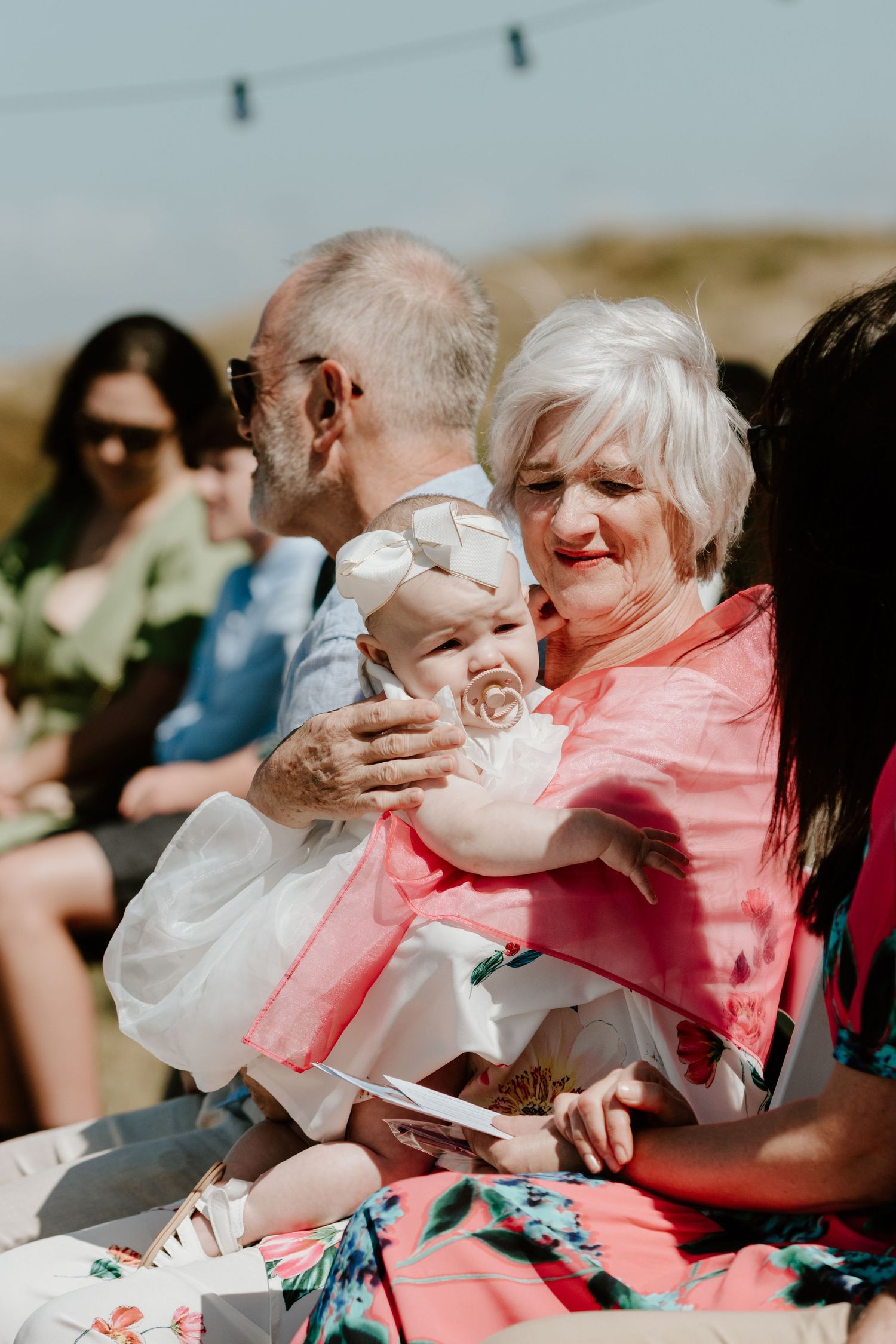 Joyful wedding guests sharing an emotional moment during outdoor beach ceremony. Papamoa Surf Lifesaving Club Wedding