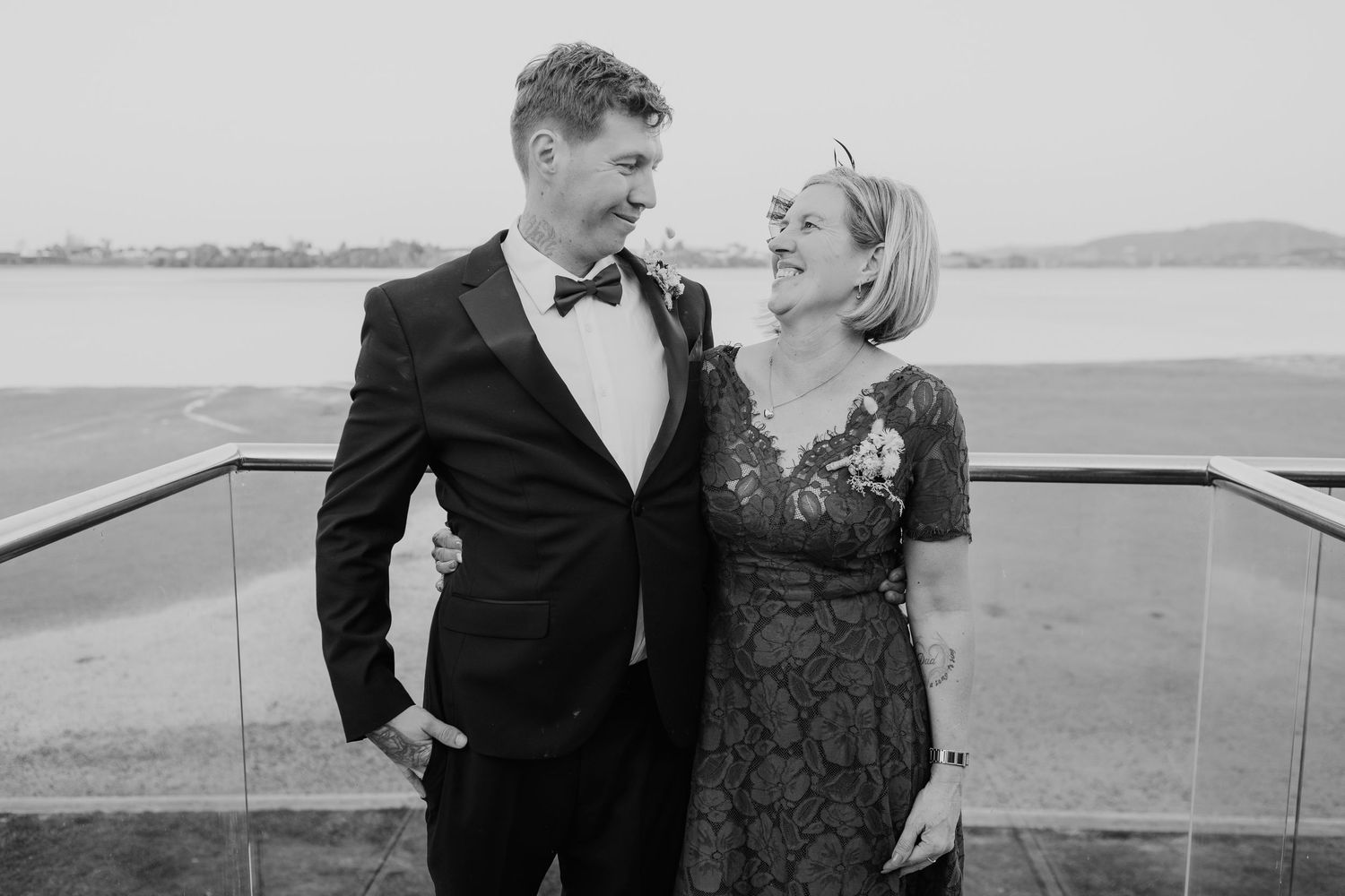 Romantic couples portrait in formal attire captured in black and white by waterfront.