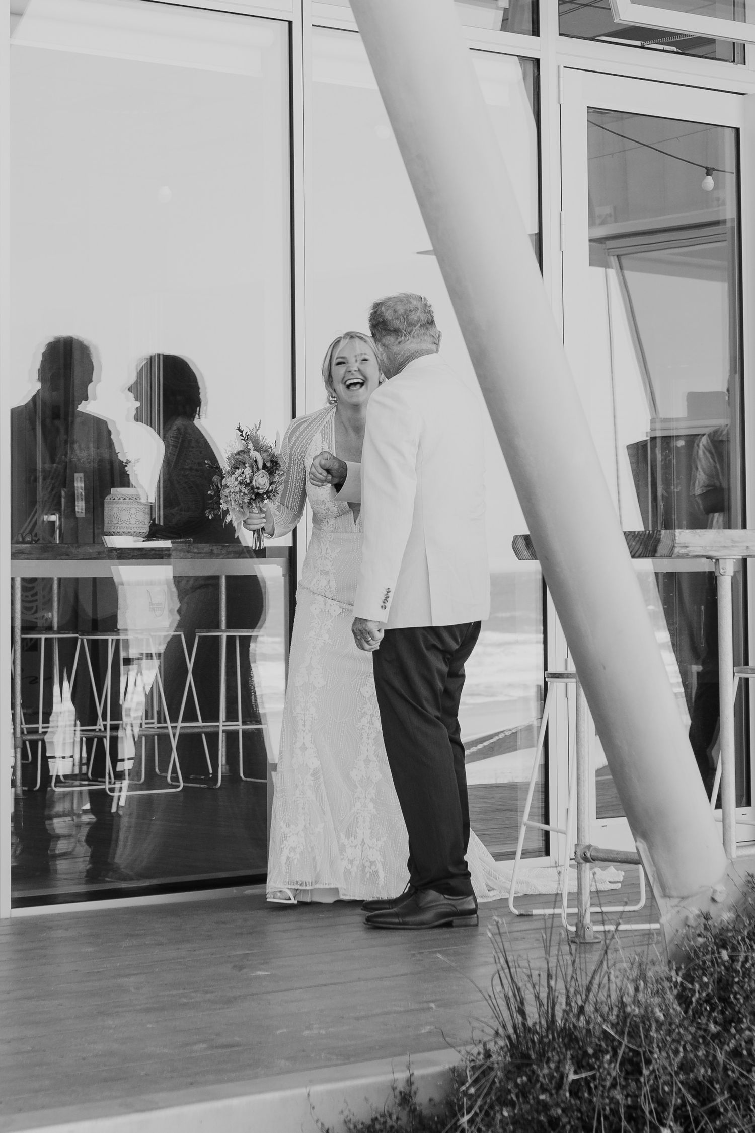 Black and white photo of a couple sharing an intimate moment at their modern venue reception. Papamoa Surf Lifesaving Club Wedding
