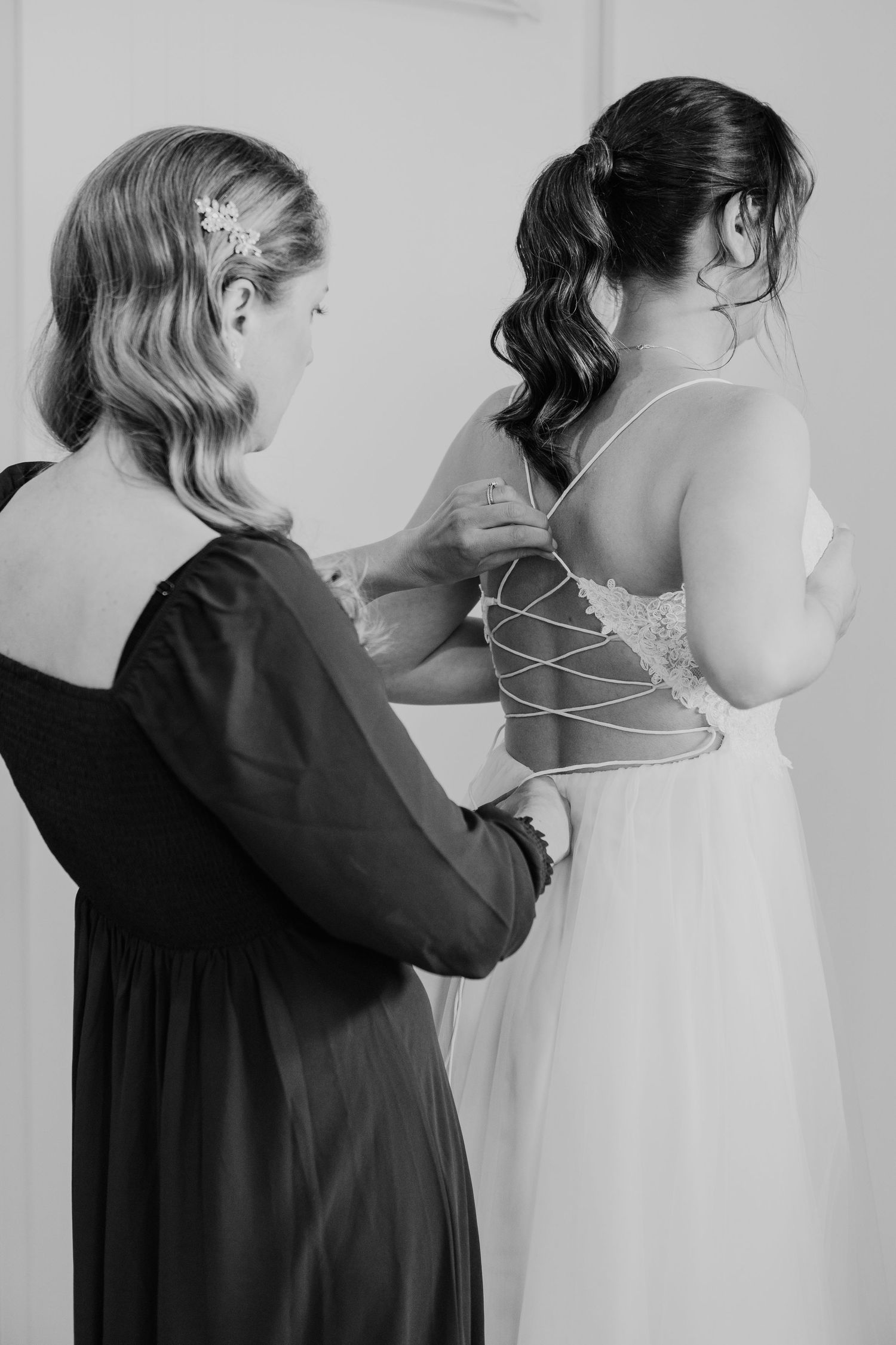 Close-up of wedding dress being laced up in classic black and white photography.