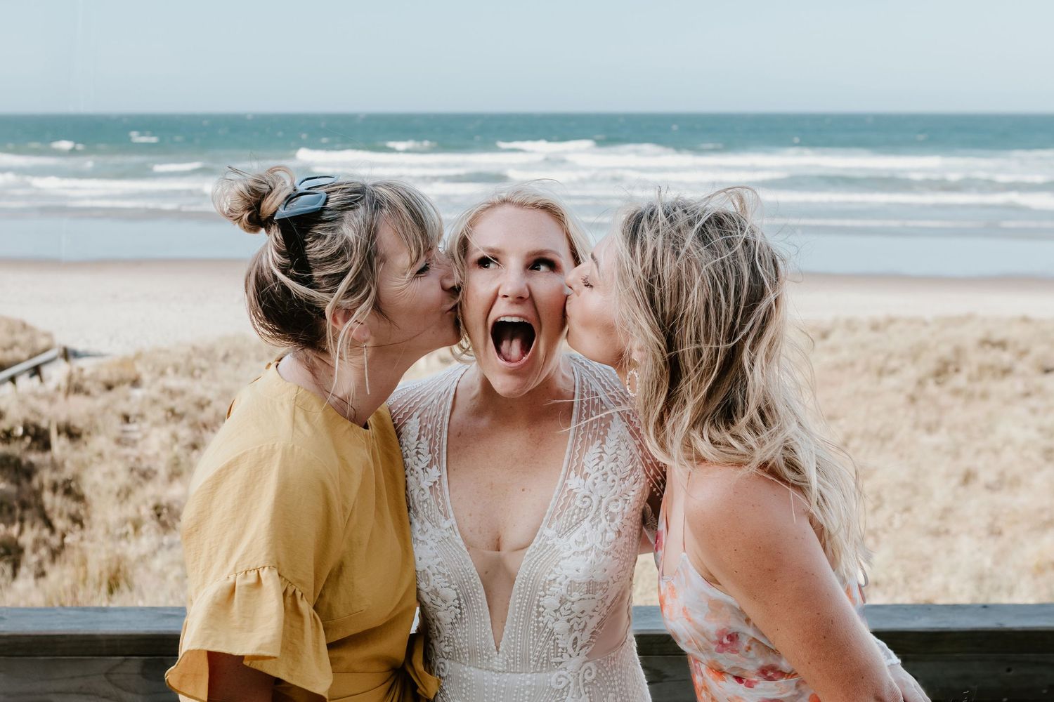 Guests laughing and celebrating at a beachside wedding with ocean views. Papamoa Beach Wedding