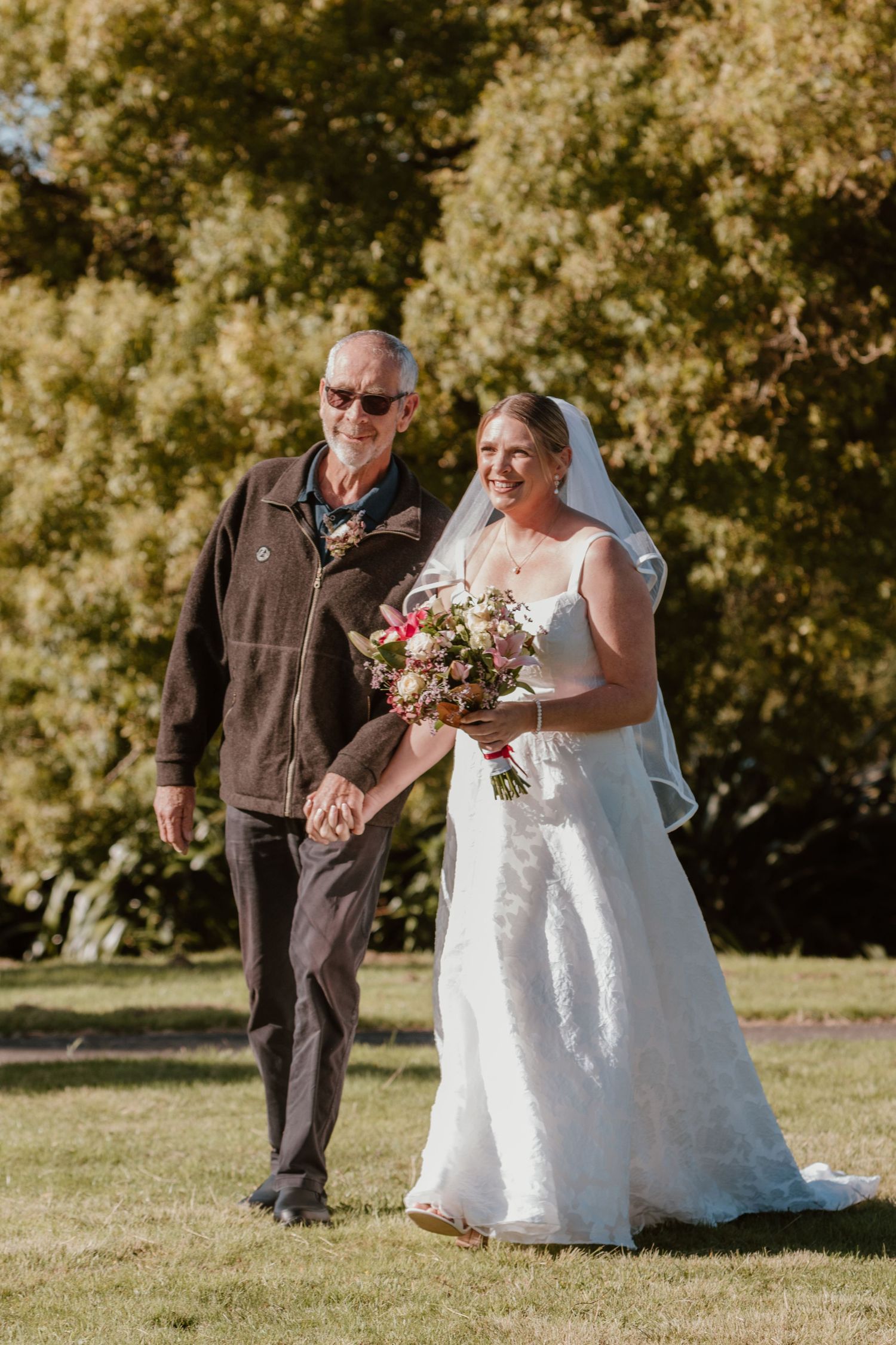 A heartwarming wedding moment captured outdoors with fall foliage in the background.