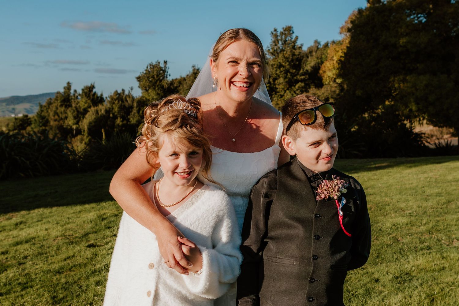 Happy couple celebrates their wedding day in a sunlit outdoor field during golden hour.