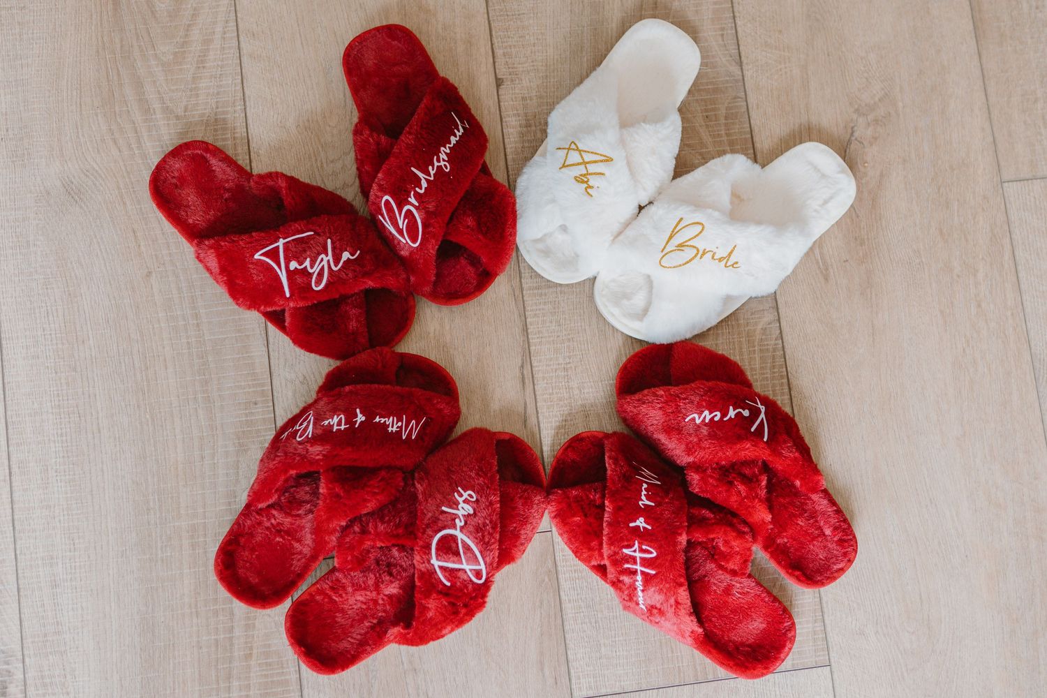 Red and white plush heart pillows lined up on a light wooden floor make a romantic Valentine's day display.