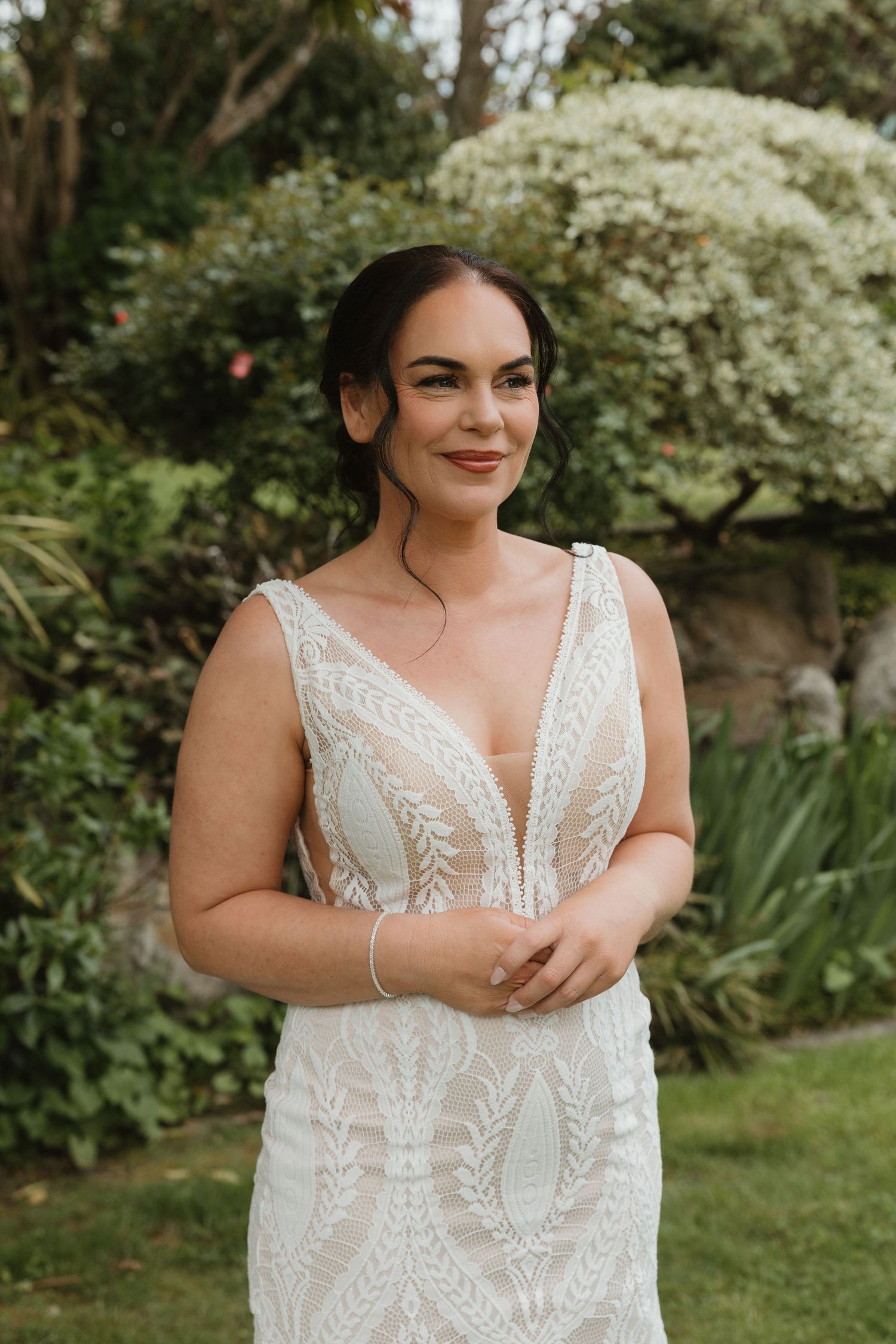 A series of photos showing a white lace wedding dress with delicate leaf patterns and a plunging V-neckline in an outdoor setting.
